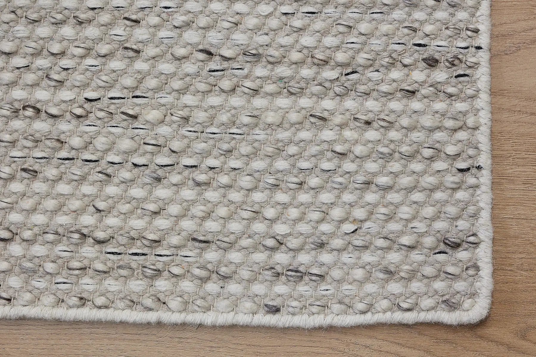 Boa - Salt & Pepper is a hand-woven flatweave, made of wool with a pile height of 7-9mm. Colours White with Black and Grey  accents. Sizes 160 X 230, 200 X 290, and 240 X 340. Corner.