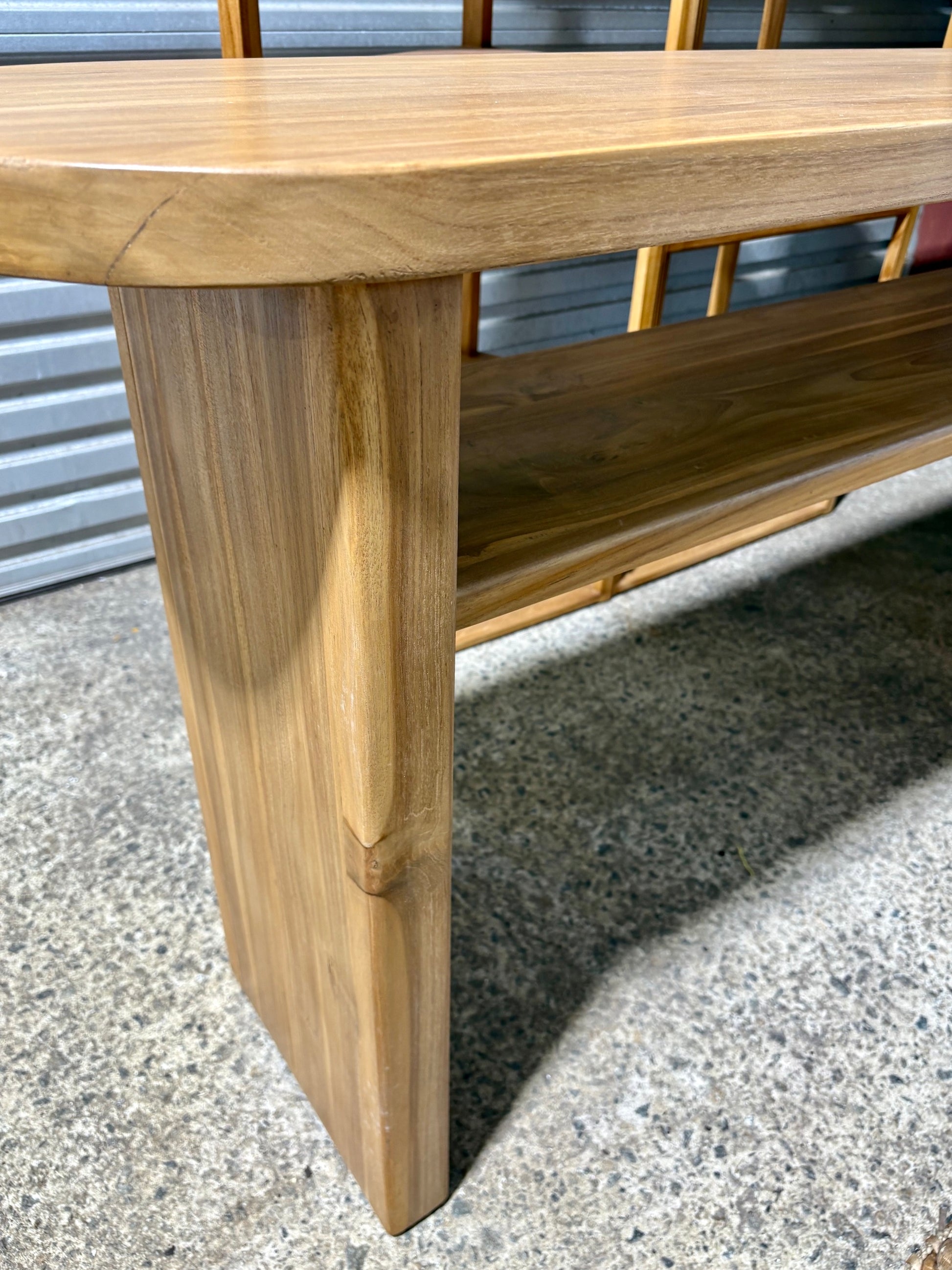 Budapest Console crafted from solid teak. Featuring  an added shelf, 2 solid legs and solid top with rounded ends. Colour Natural Teak. Measures 1800 Wide X 400 Depth X 800 Height. Angle.