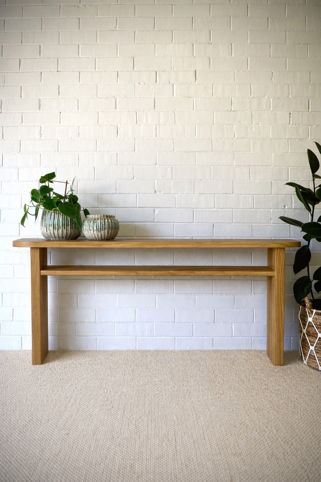 Budapest Console crafted from solid teak. Featuring  an added shelf, 2 solid legs and solid top with rounded ends. Colour Natural Teak. Measures 1800 Wide X 400 Depth X 800 Height. Styled.