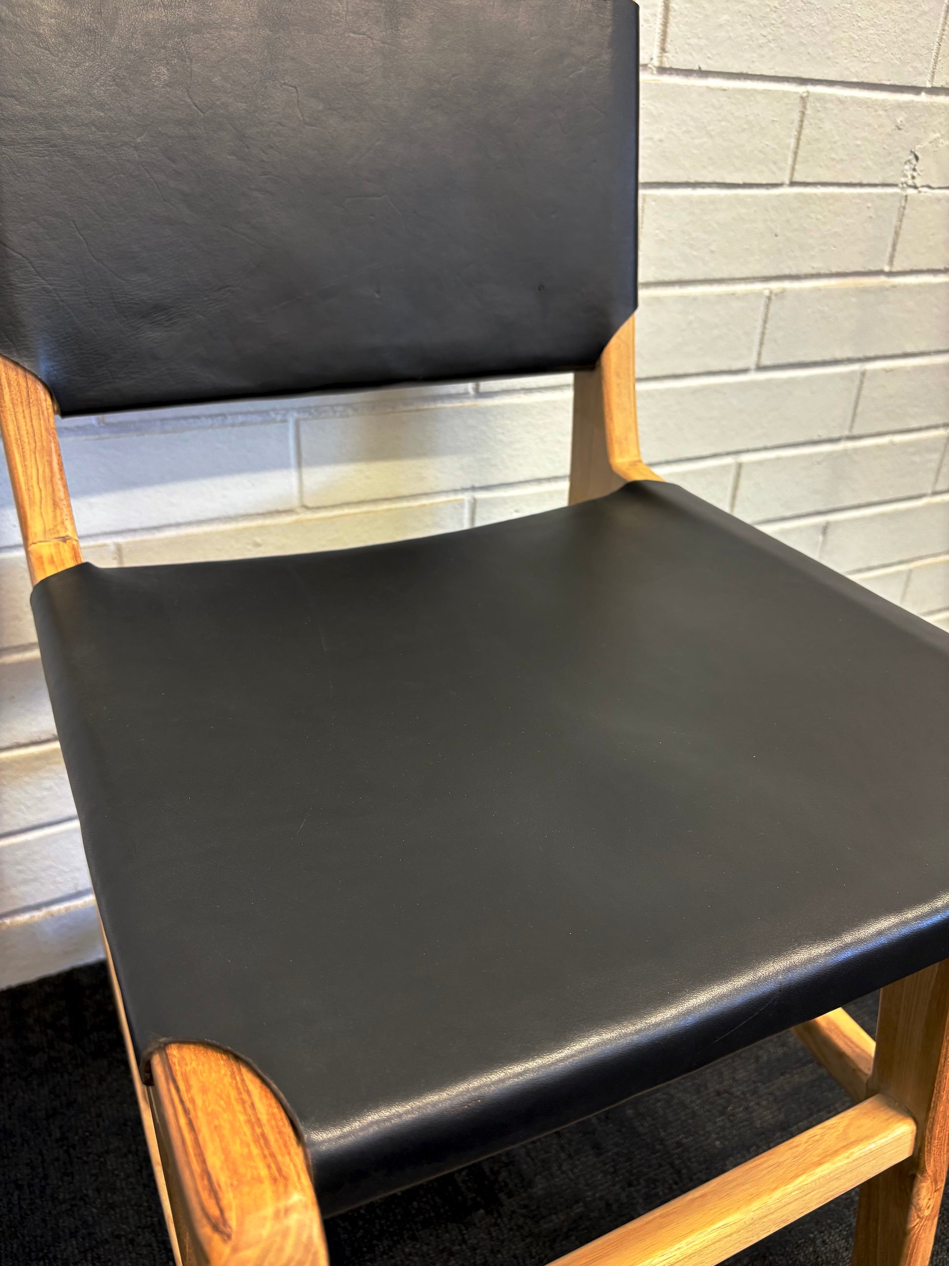 The Cherokee - Black Dining Chair is crafted from solid teak with a smooth black leather seat and back. Colours natural frame with black seat and back. Measures 560 Depth x 450 Wide x 500 Seat Height. Back height 820. Close.