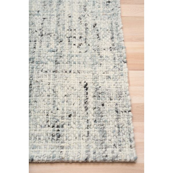 Cleo Blue hand-woven wool flatweave rug in a soft blue-grey tone, with a flecked, cross-woven texture and flat woven border. 3 Sizes. Corner view.