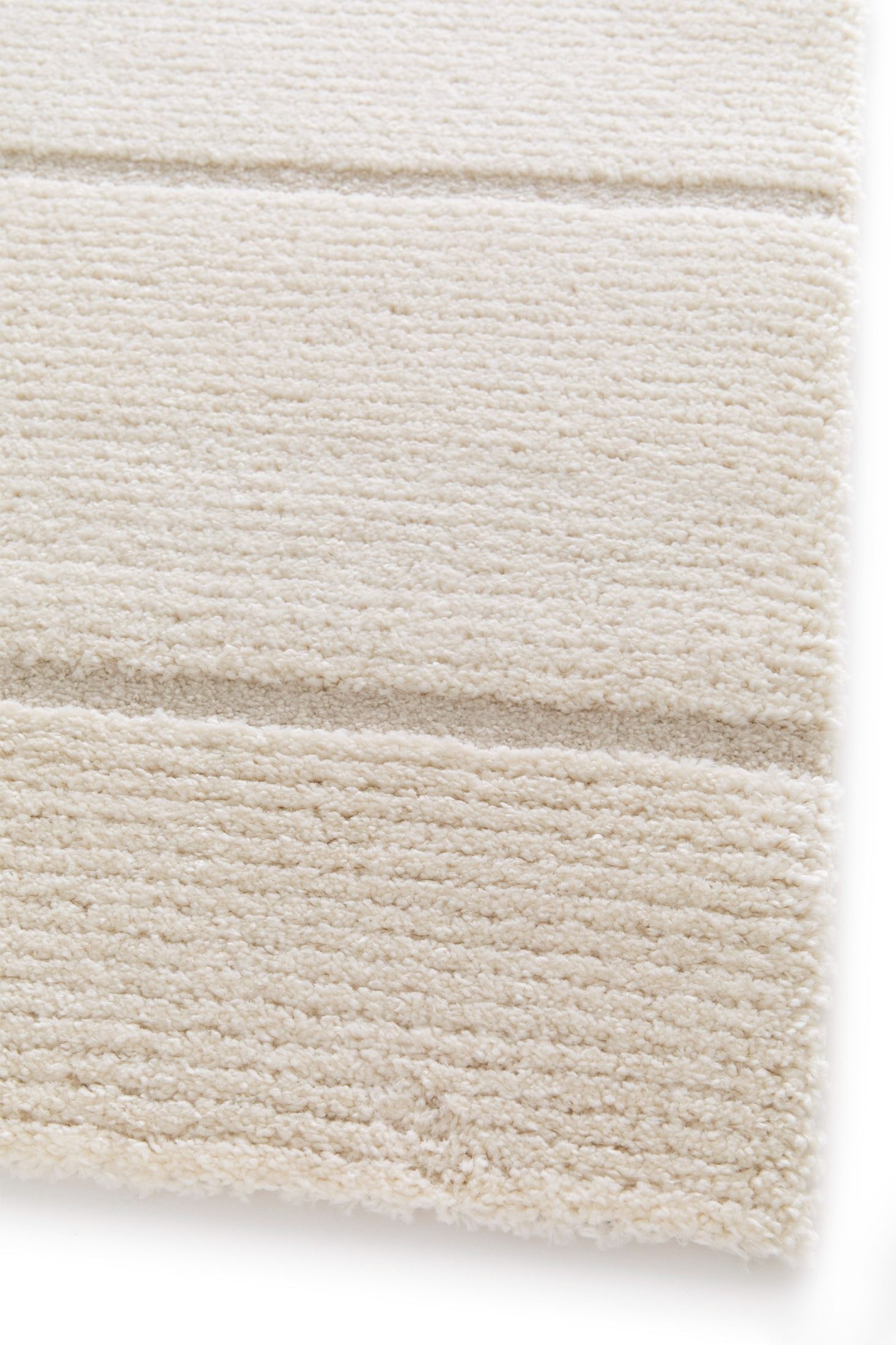 Cocoon - Cream, a modern rug design crafted with a unique blend of Heat Set Polypropylene and Polyester shrink yarn. Corner.