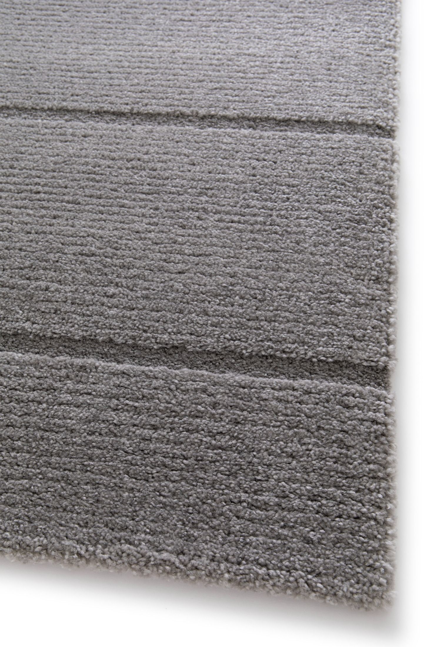 Cocoon - Grey, a modern rug design crafted with a unique blend of Heat Set Polypropylene and Polyester shrink yarn. Corner.