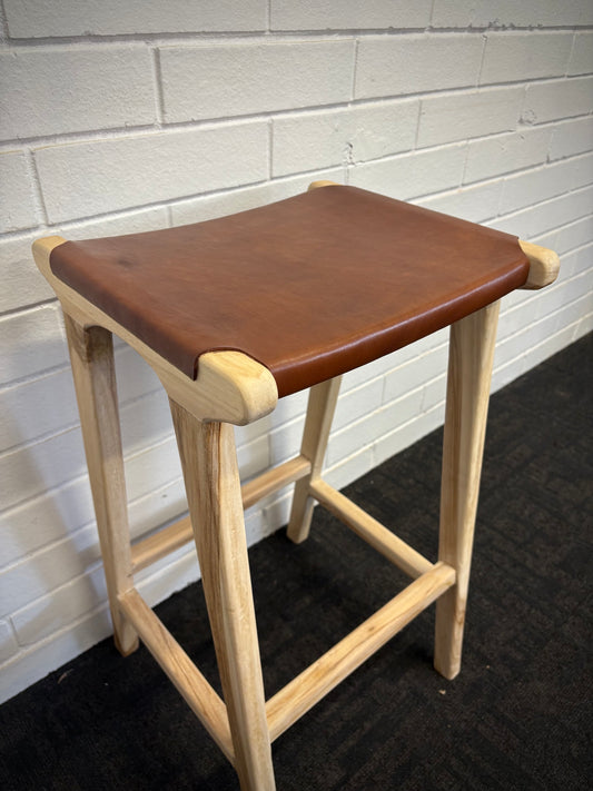 The Columbia - Brown Leather barstool features a lush leather seat and sustainable teak framed legs. Colour natural teak frame with brown leather seat. Measures 400 wide X 400 depth X 650 Seat height. Angle.