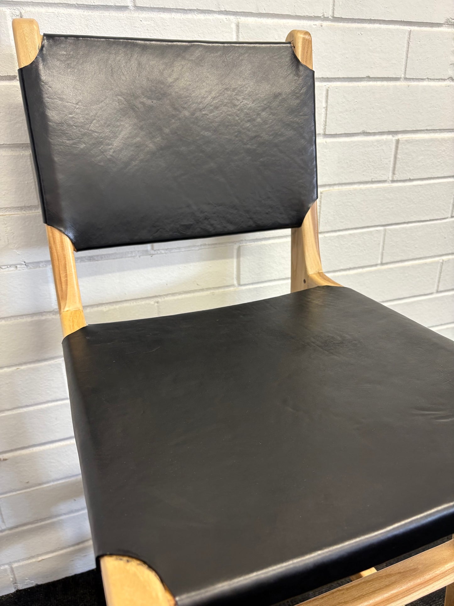 The Columbia with Back - Black Leather barstool features a black leather seat and back with sustainable teak framed legs. Colour natural teak frame with black leather seat and back. Measures 400 wide X 400 depth X 680 Seat height X 1000 Back height. Close.