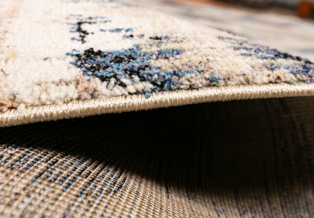 Cozy 5439 Blue Beige is a tribal diamond patterned designed machine made rug. Constructed from luxurious polyester yarn, it features a soft feel.  Colours Beige with Cream, Blue and Black Diamond Patterns. Sizes  160 X 230 and 200 X 290 and 300 X 400. Side.