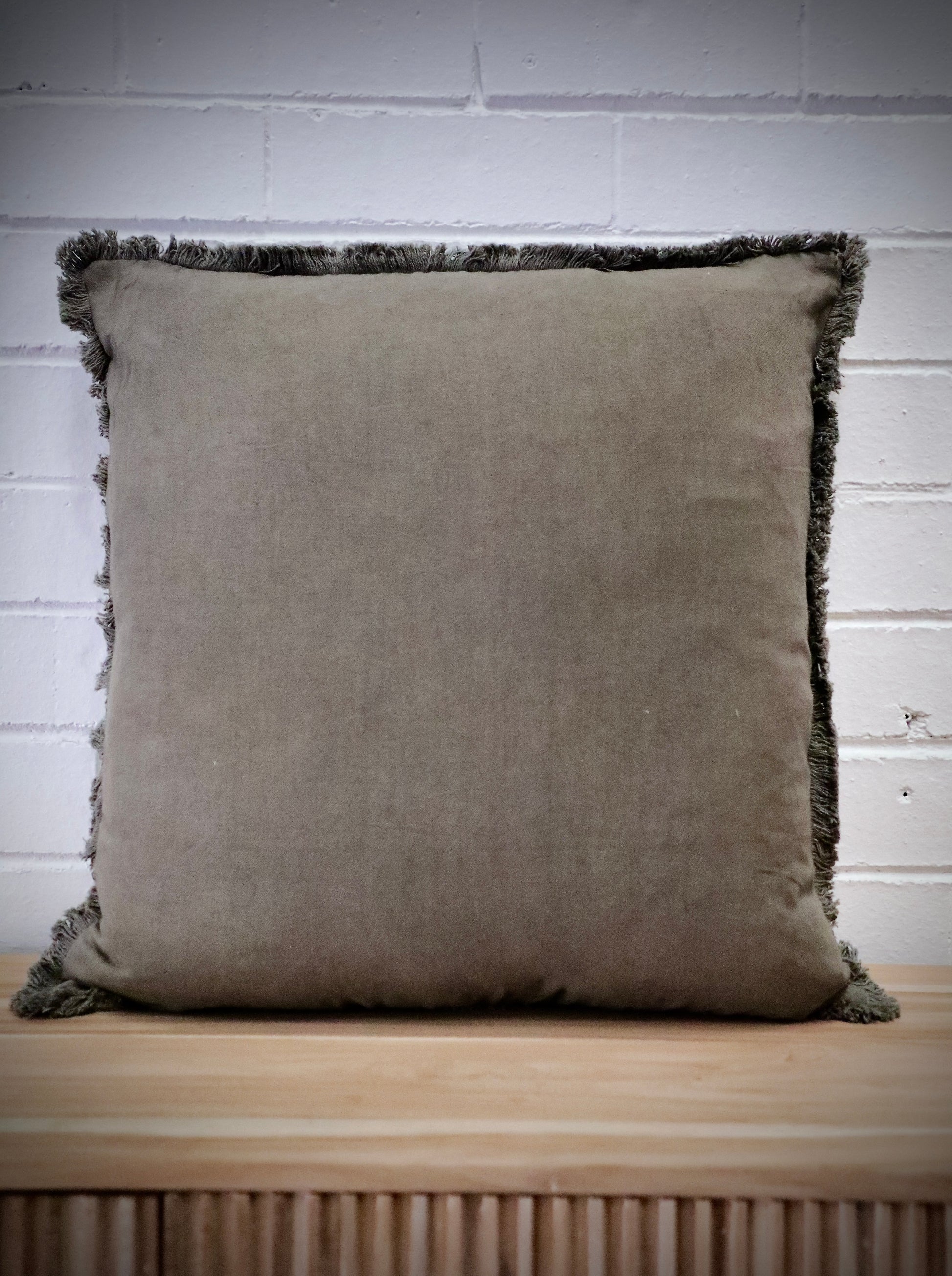 The Dusty Olive, green, throw cushion is crafted by skilled artisans in India. Made of cotton it boasts a contemporary style with a smooth luxurious cotton weave and a fringed edge. Colour green. Sizes, 50 X 50 and 60 X 60. Front.