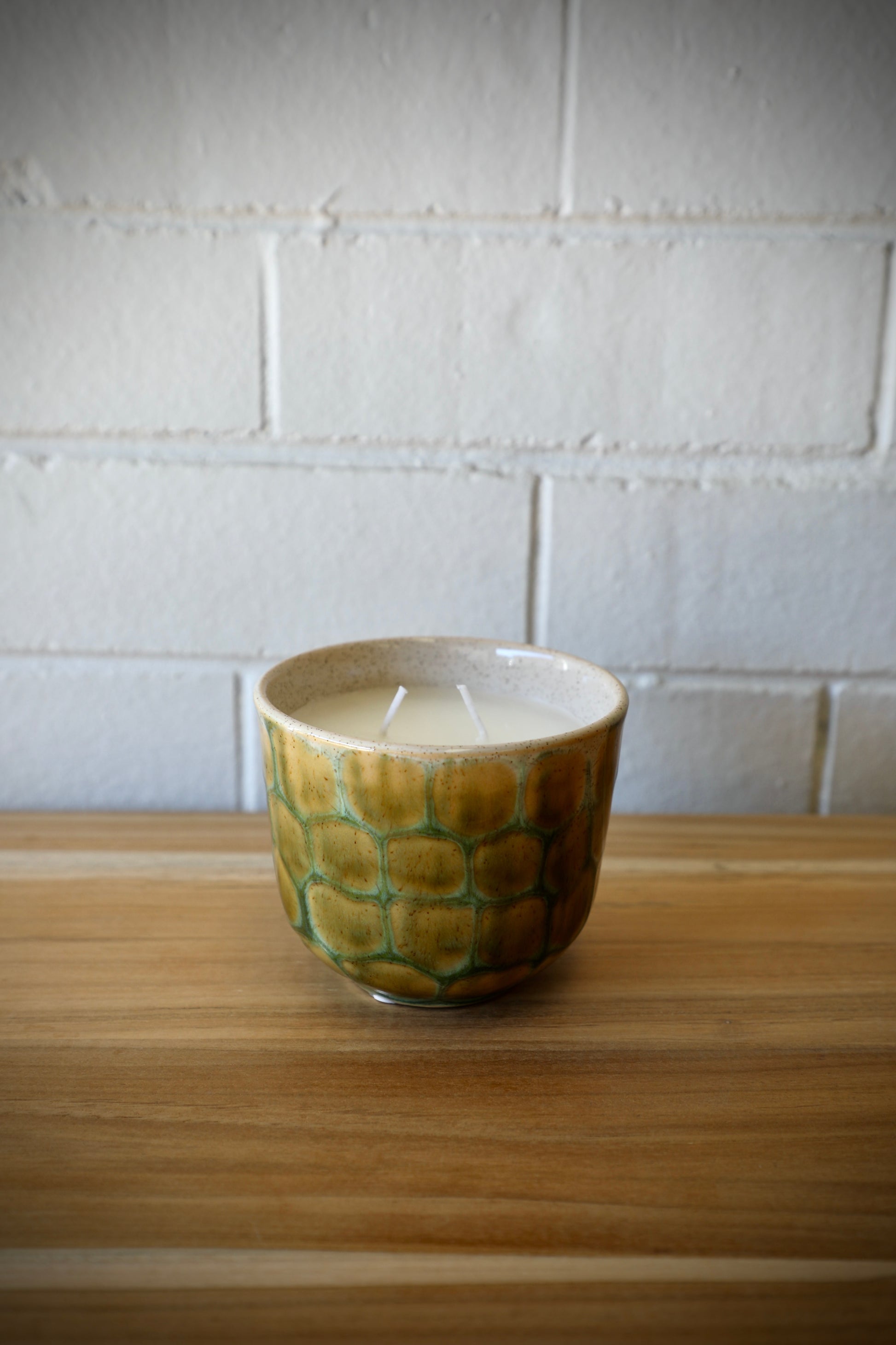 The Finch Ceramic Candle features a patched scaled design.  Featuring a lemon grass scent, it's sure to bring a soothing sense to any room. Colours, cream, browns and beiges. Measures 11 Diameter X 9 Height. Side Styled.
