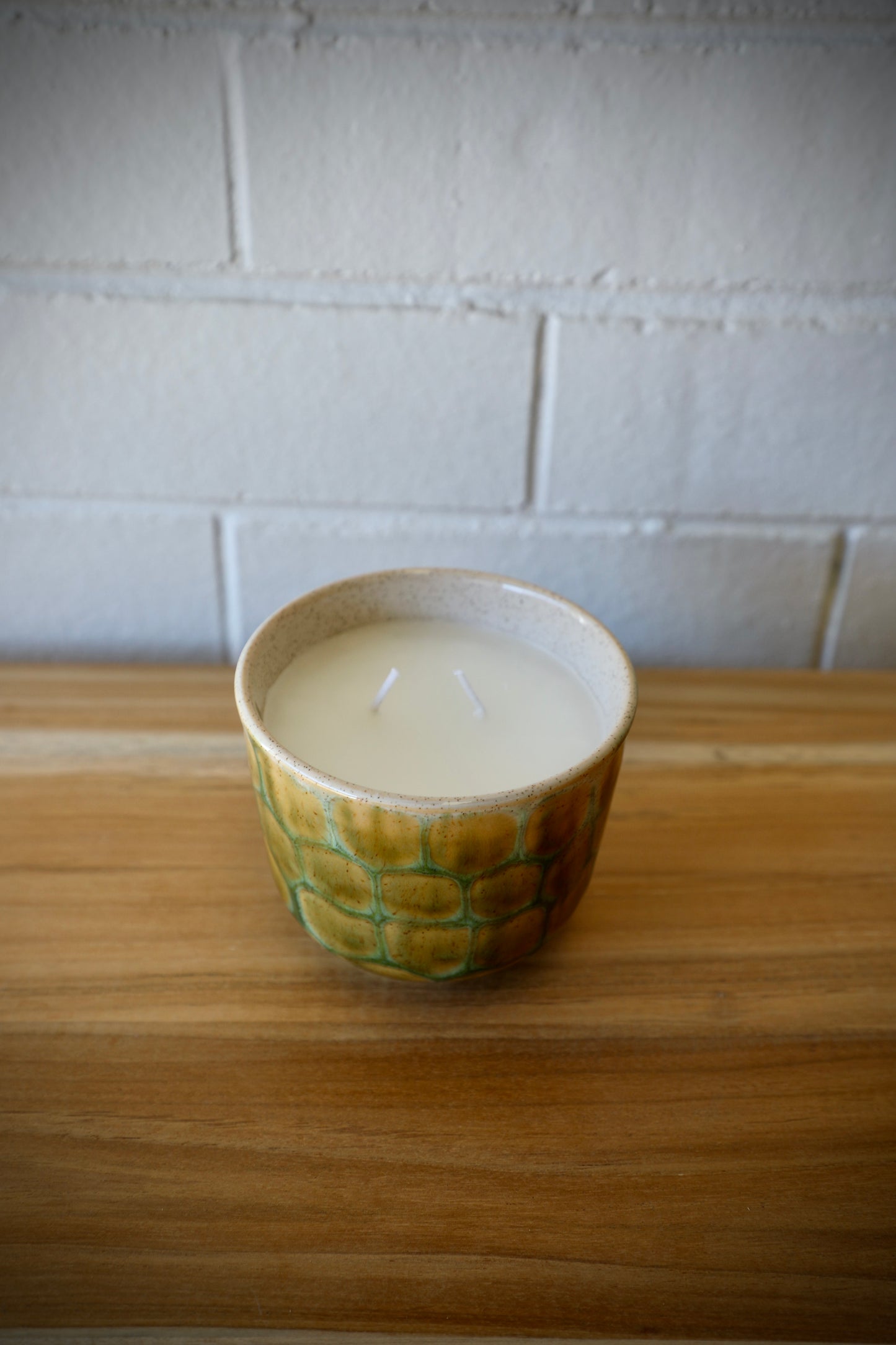 The Finch Ceramic Candle features a patched scaled design.  Featuring a lemon grass scent, it's sure to bring a soothing sense to any room. Colours, cream, browns and beiges. Measures 11 Diameter X 9 Height. Top Styled.