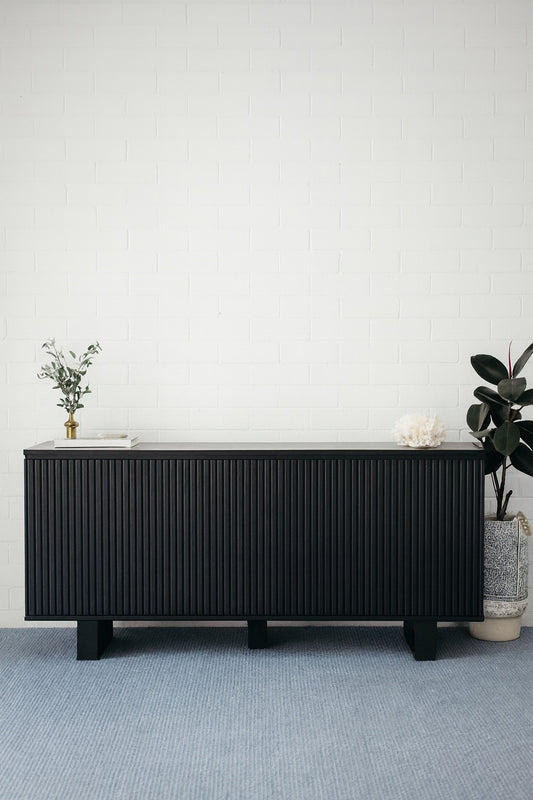 The Florence Black Buffet. 4 textured doors with smart storage behind the left door featuring 4 drawers. Colour Black. Measures 1800 wide X 400 depth x 900 height. Styled.