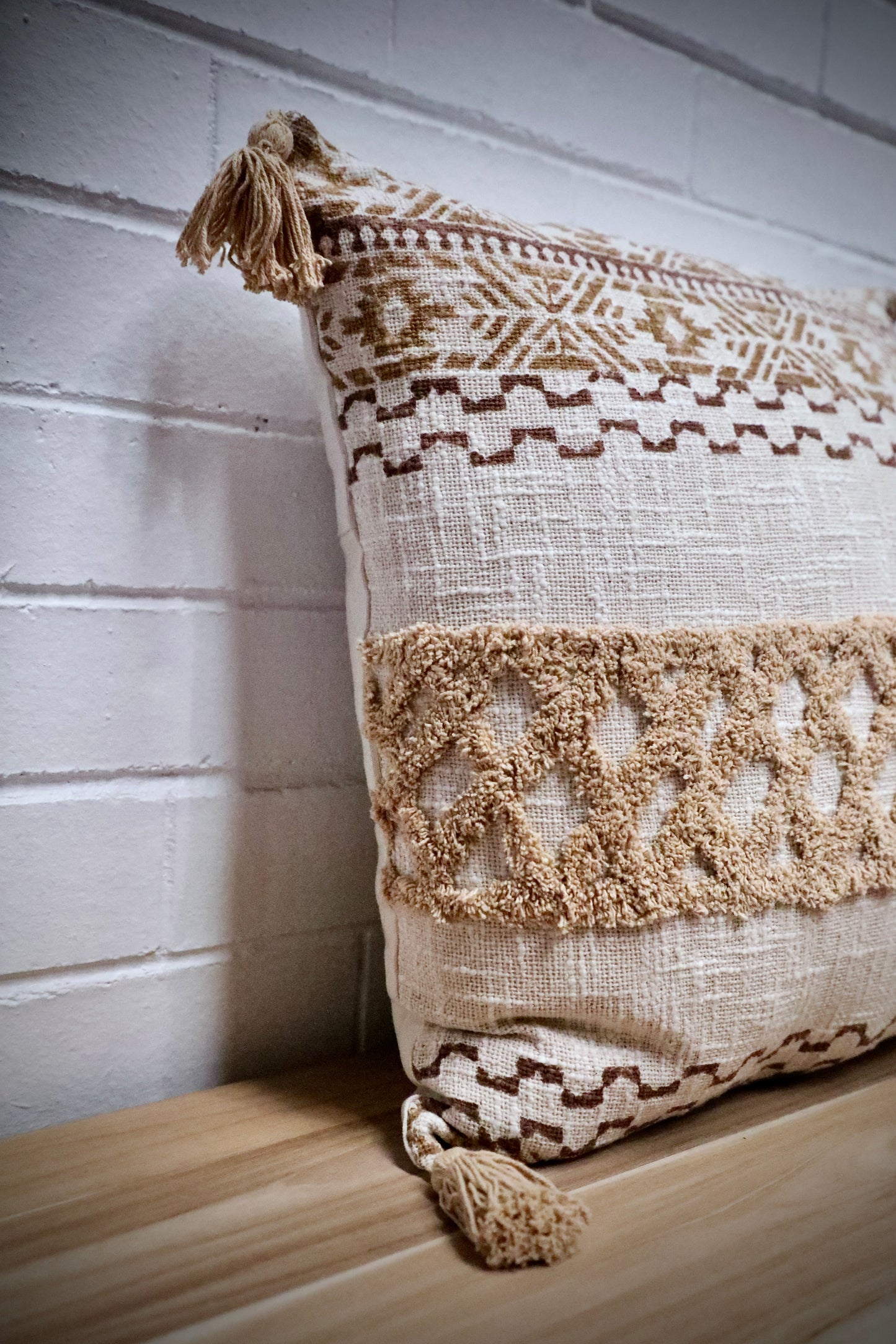 The Folk Tale block print in hand crafted in India.  Made from durable soft cotton, it features geometric designs and a textured pattern with tasseled corners.  Colours, beige, oranges, browns and greys.  Measures 50 X 50. Angle.