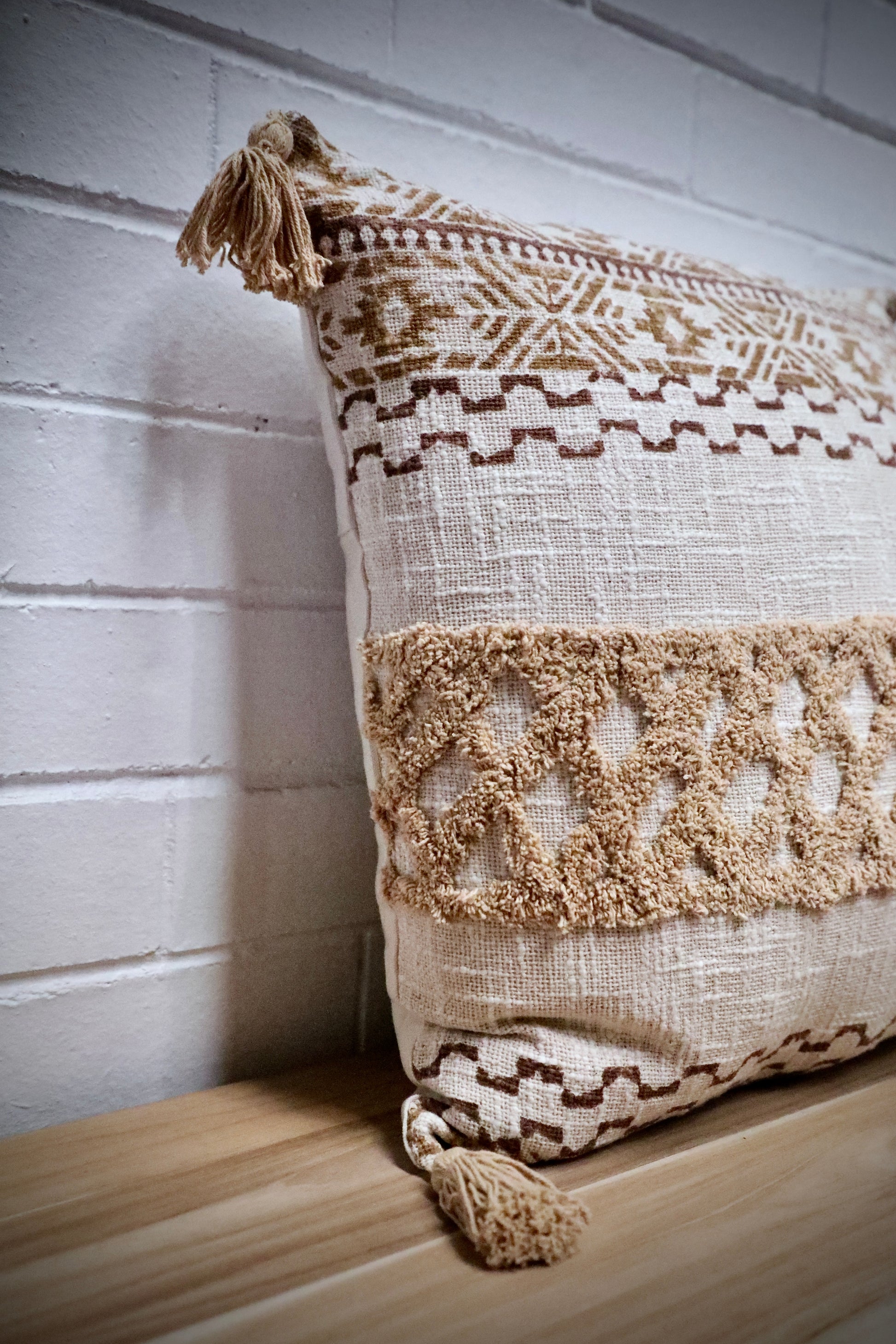 The Folk Tale block print in hand crafted in India.  Made from durable soft cotton, it features geometric designs and a textured pattern with tasseled corners.  Colours, beige, oranges, browns and greys.  Measures 50 X 50. Angle.
