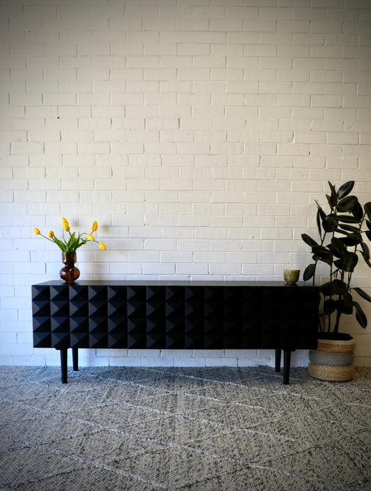 The Gable 2 Door 2 Drawer Entertainment Unit. A modern designed unit featuring a pyramid textured front and Sleek turned legs. Colour Black. Measures 1800L x 420D x 670H. Styled.
