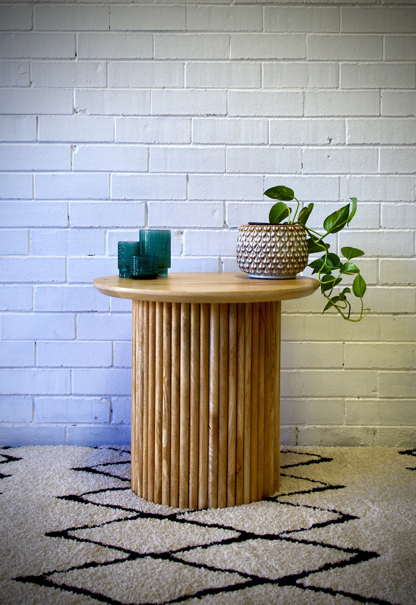 The Hakone Side Table features a contemporary textured round base and a smooth round top. Crafted from sustainable fruitwood. Colour natural. Measures 600 diameter X 550 height. Front Styled.