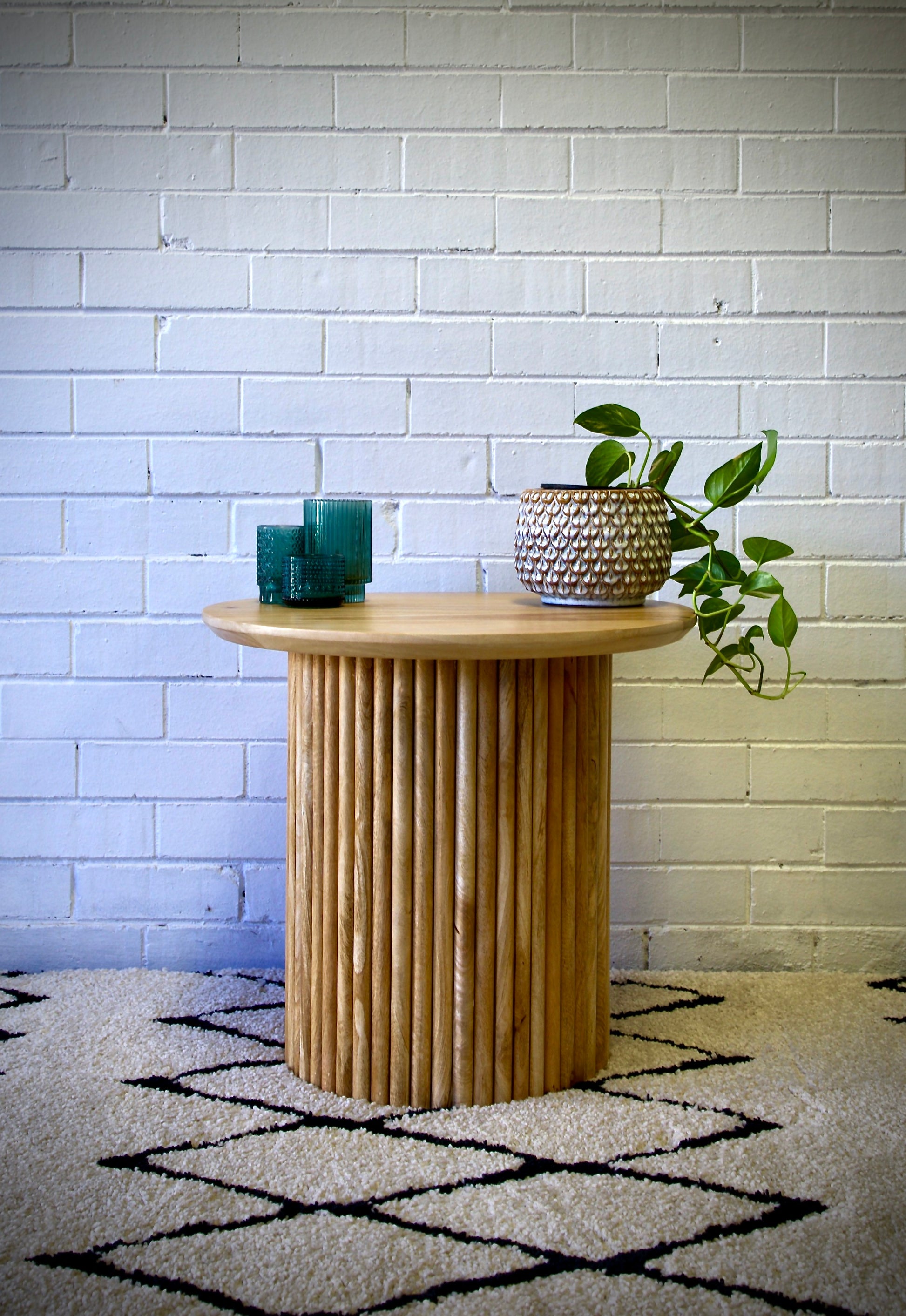 The Hakone Side Table features a contemporary textured round base and a smooth round top. Crafted from sustainable fruitwood. Colour natural. Measures 600 diameter X 550 height. Front Styled.