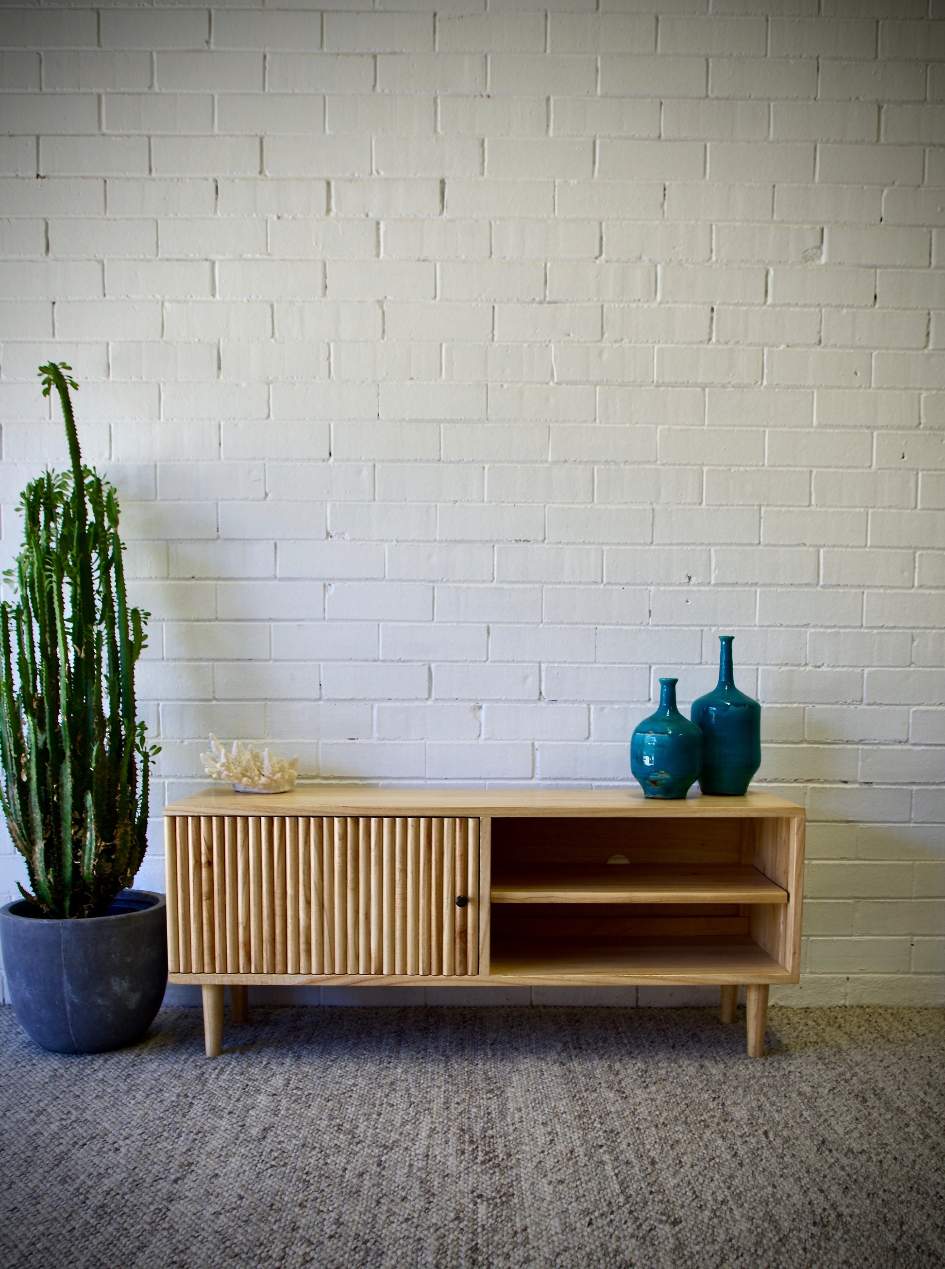 The Hepburn 1 Door Entertainment Unit is crafted from sustainable white cedar, featuring a textured door and an open shelf. Colour natural. Measures 1200 length X 360 depth X 500 height. Front Styled.