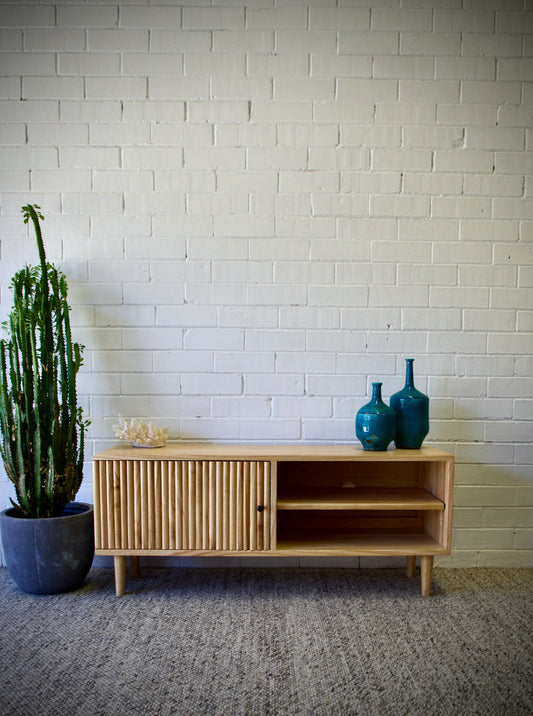 The Hepburn 1 Door Entertainment Unit is crafted from sustainable white cedar, featuring a textured door and an open shelf. Colour natural. Measures 1200 length X 360 depth X 500 height. Front Styled.