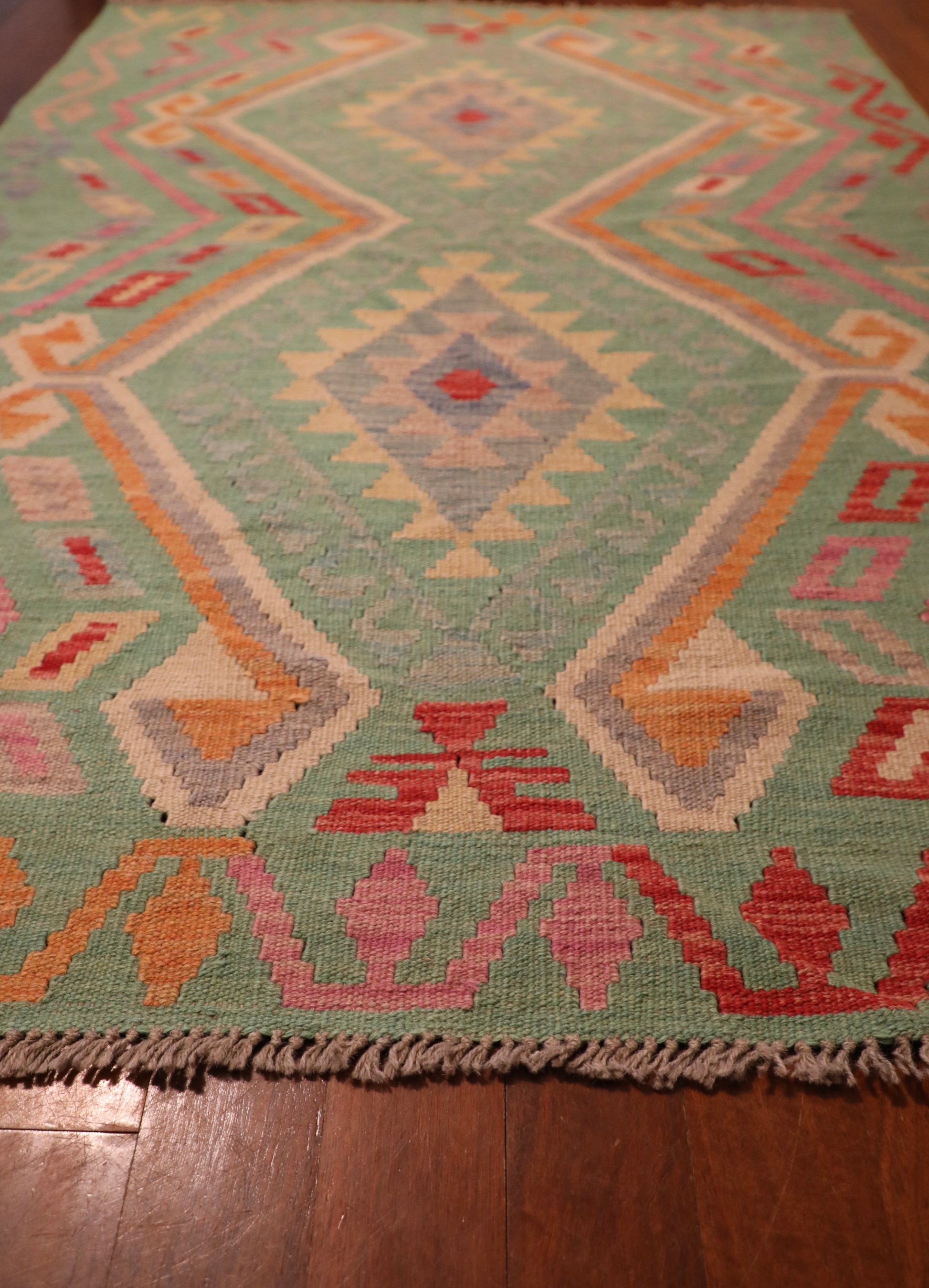 The Afghan Hand Woven Khyber Kilim - 126 X 179. Crafted using traditional vegetable dyed wool, and featuring traditional geometric designs. Colours, greens, beiges, creams, oranges. Size 126 X 179. Angle.