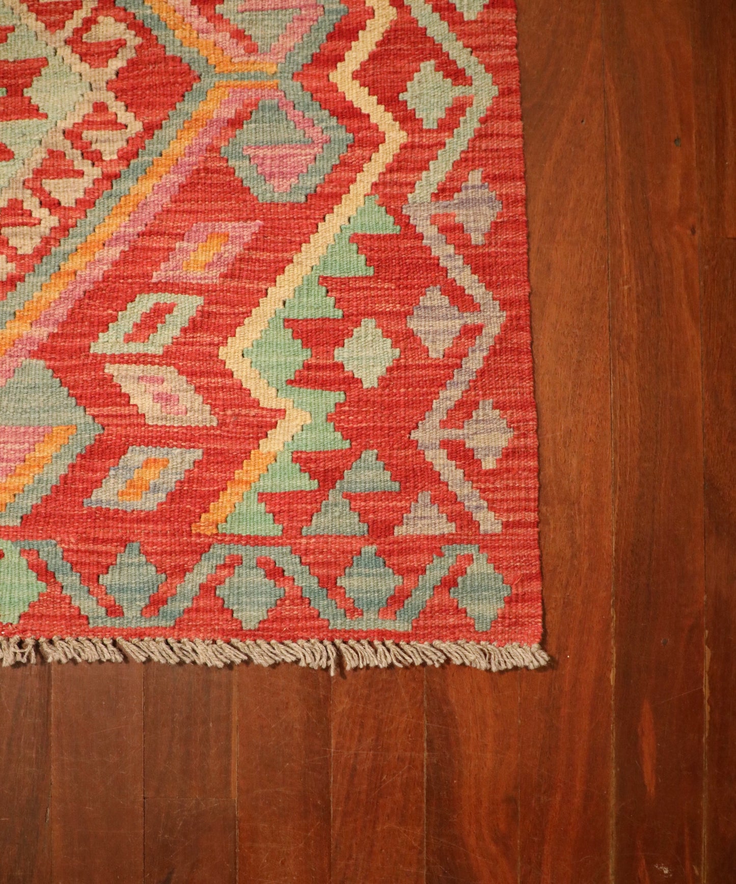 The Afghan Hand Woven Khyber Kilim - 124 X 176. Crafted using traditional vegetable dyed wool, and featuring traditional geometric designs. Colours, Oranges, beiges, creams, lavender. Size 124 X 176. Corner.