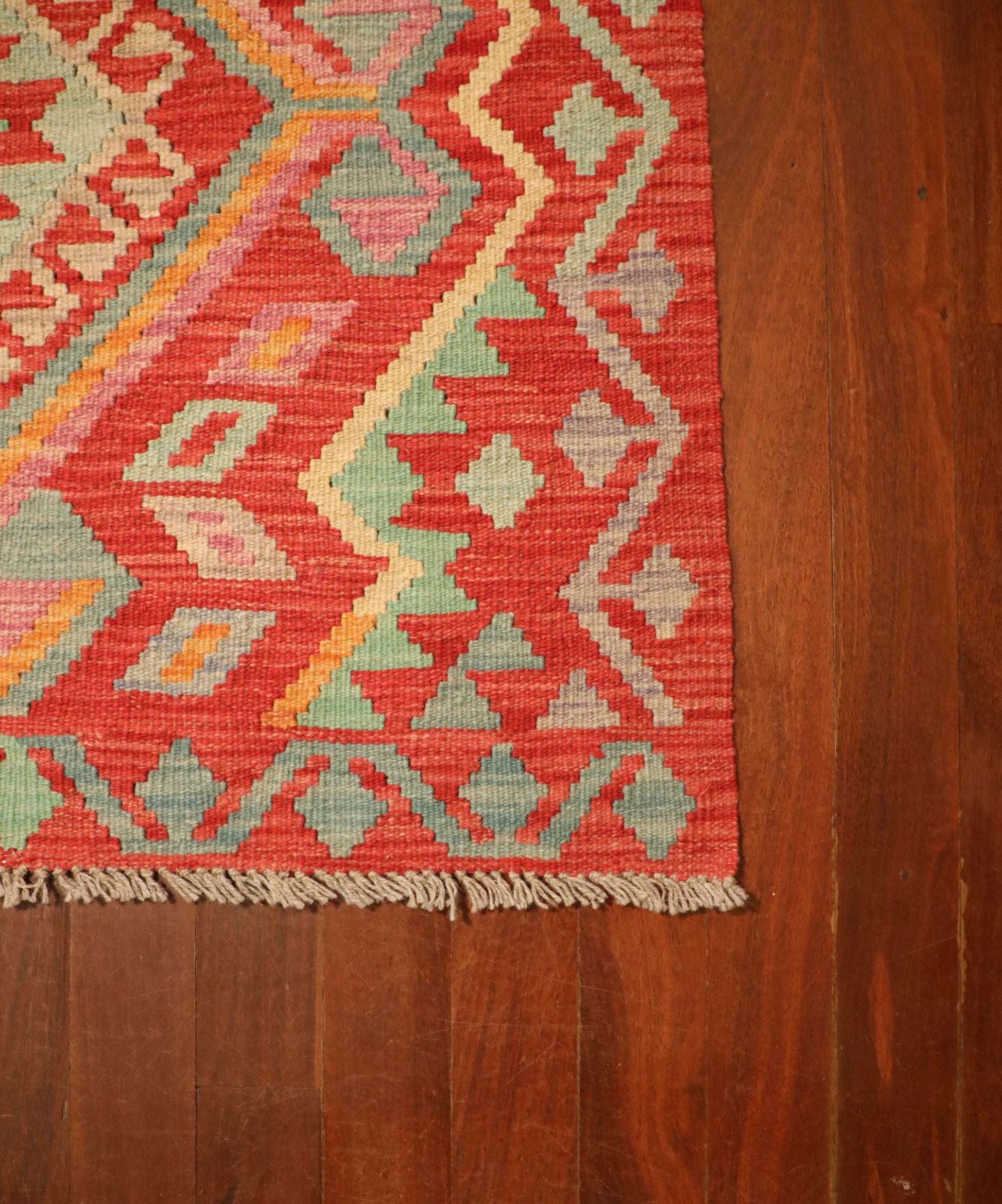 The Afghan Hand Woven Khyber Kilim - 124 X 176. Crafted using traditional vegetable dyed wool, and featuring traditional geometric designs. Colours, Oranges, beiges, creams, lavender. Size 124 X 176. Corner.