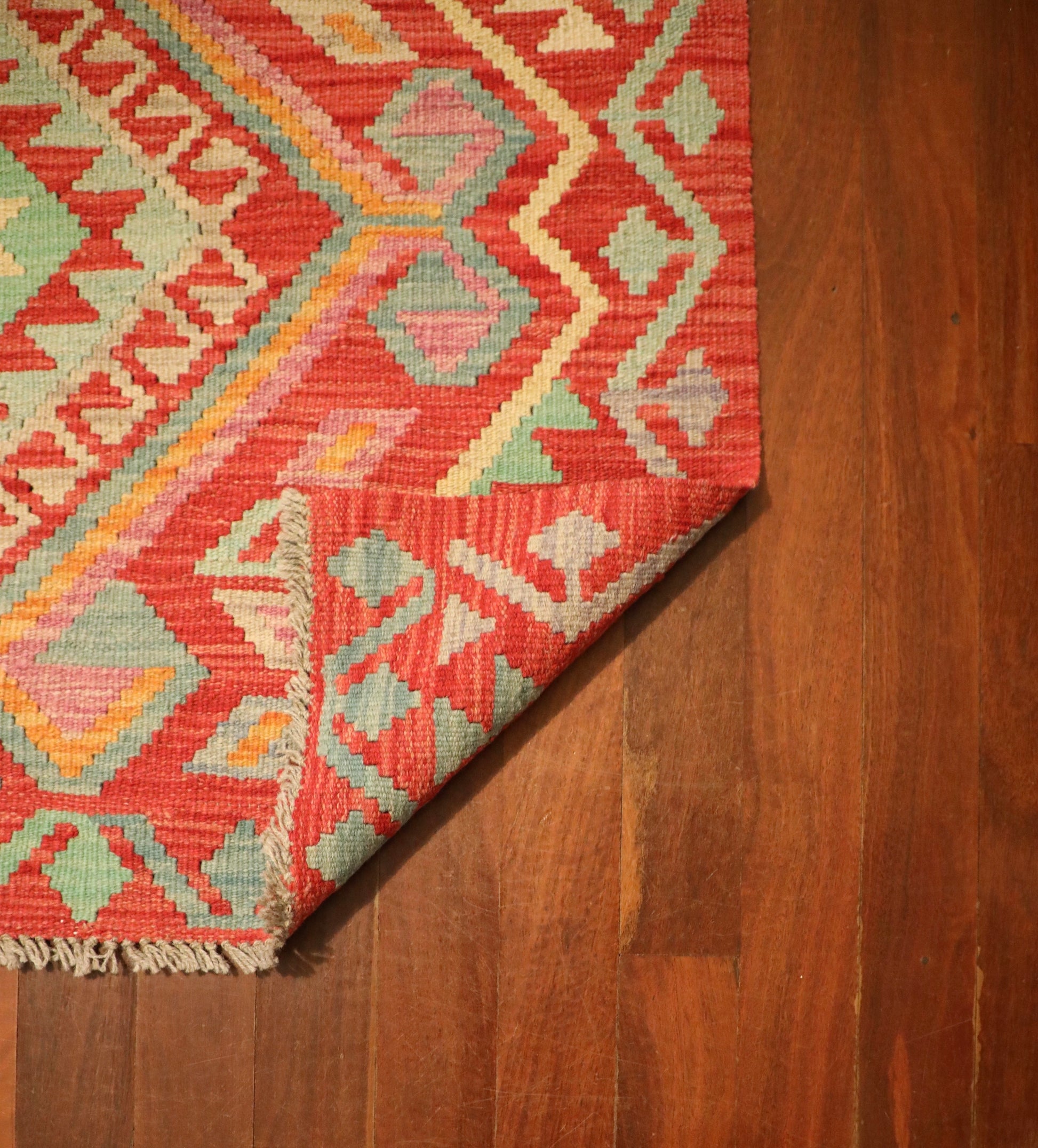 The Afghan Hand Woven Khyber Kilim - 124 X 176. Crafted using traditional vegetable dyed wool, and featuring traditional geometric designs. Colours, Oranges, beiges, creams, lavender. Size 124 X 176. Fold.