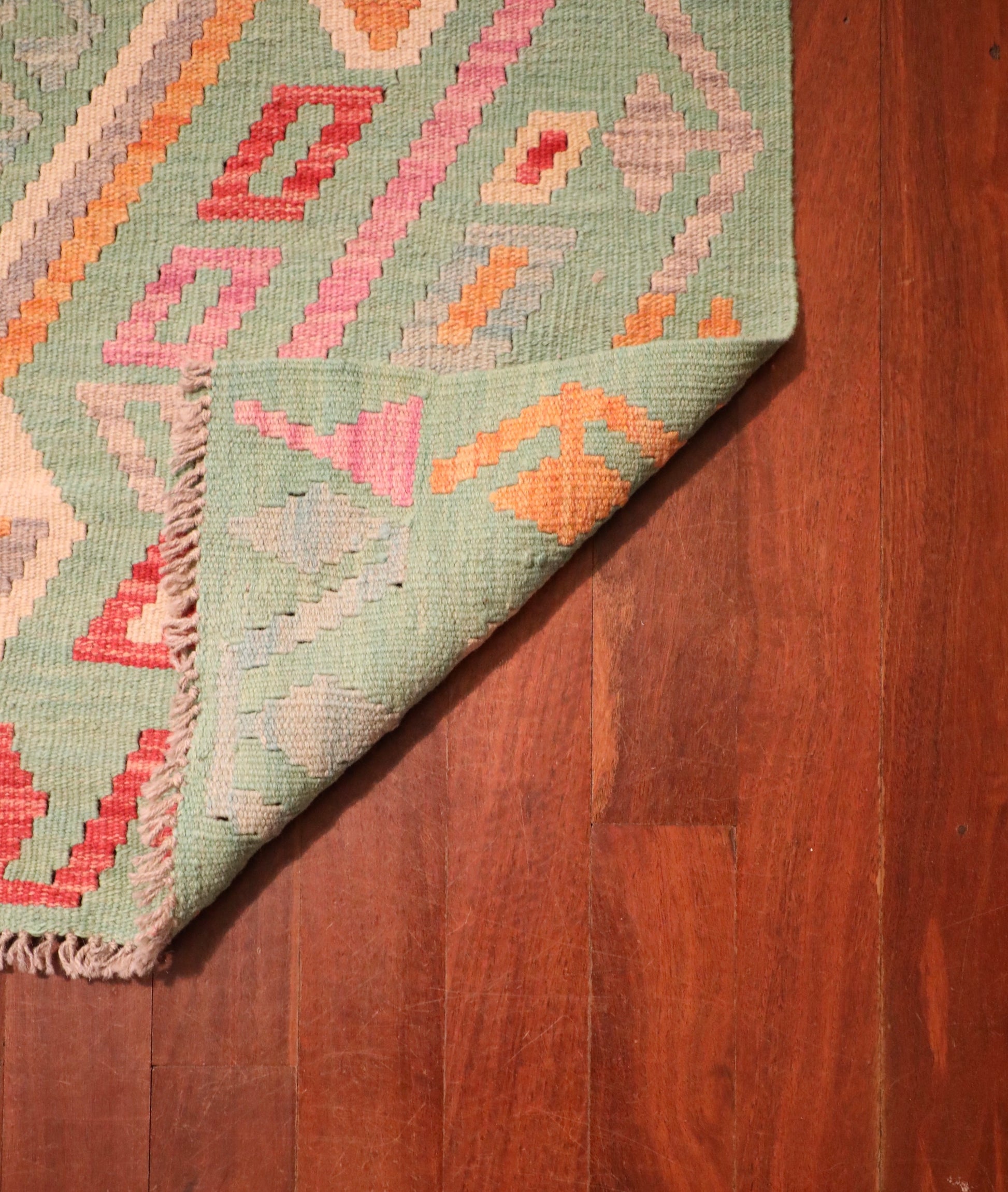 The Afghan Hand Woven Khyber Kilim - 126 X 179. Crafted using traditional vegetable dyed wool, and featuring traditional geometric designs. Colours, greens, beiges, creams, oranges. Size 126 X 179. Fold.