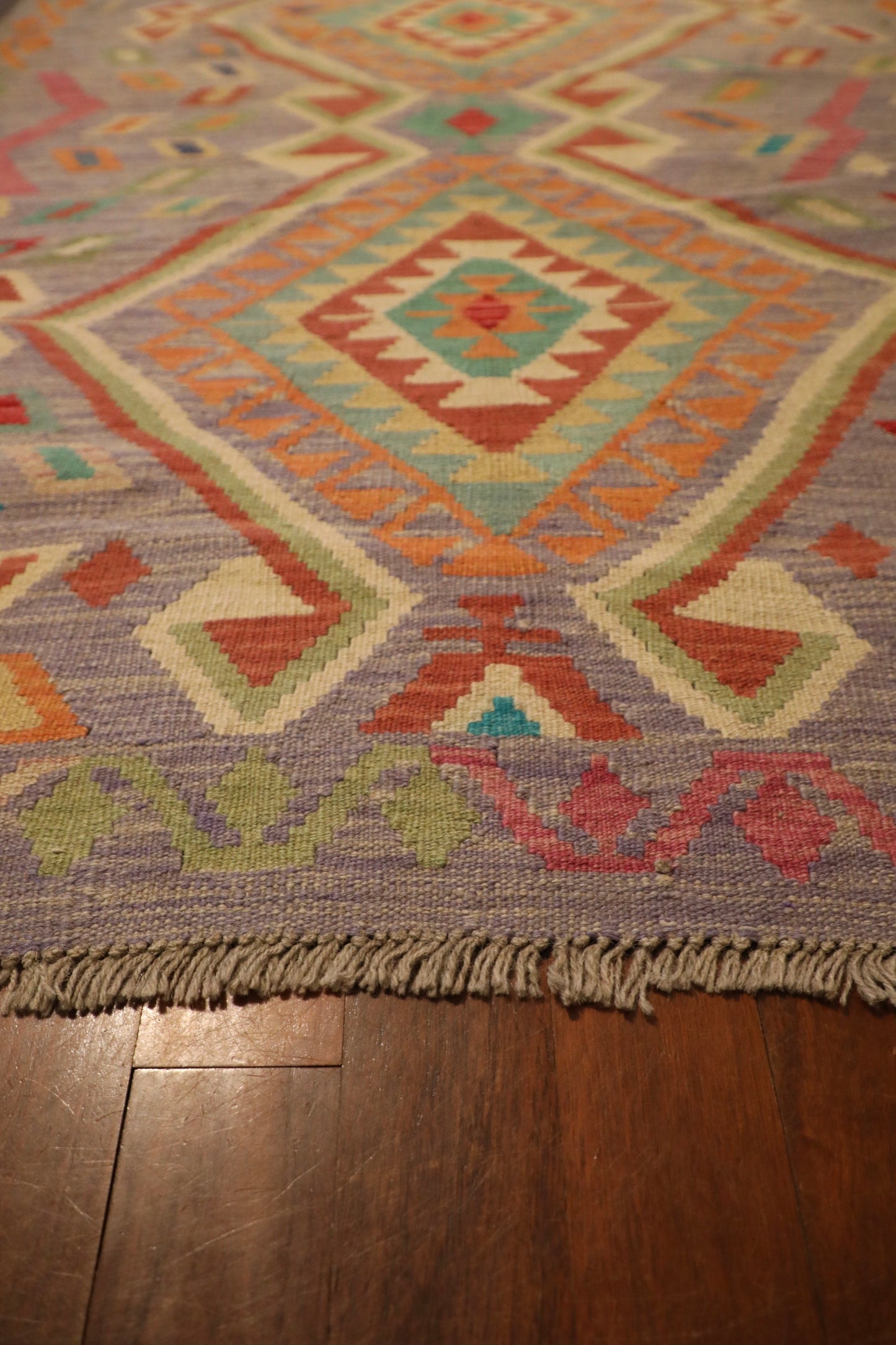The Afghan Hand Woven Khyber Kilim - 127 X 174. Crafted using traditional vegetable dyed wool, and featuring traditional geometric designs. Colours, lavenders, beiges, creams, oranges. Size 127 X 174. Angle.