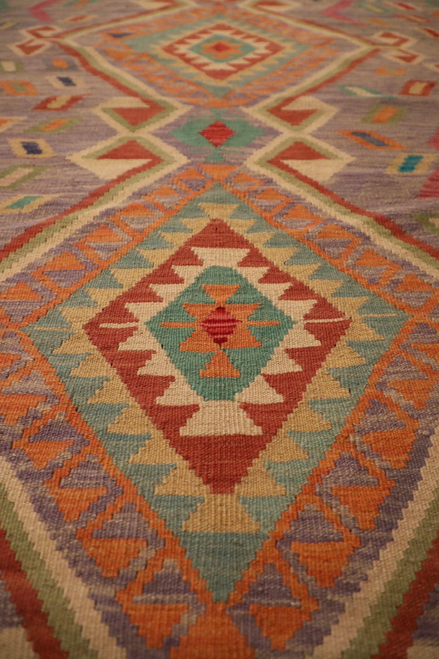 The Afghan Hand Woven Khyber Kilim - 127 X 174. Crafted using traditional vegetable dyed wool, and featuring traditional geometric designs. Colours, lavenders, beiges, creams, oranges. Size 127 X 174. Close.