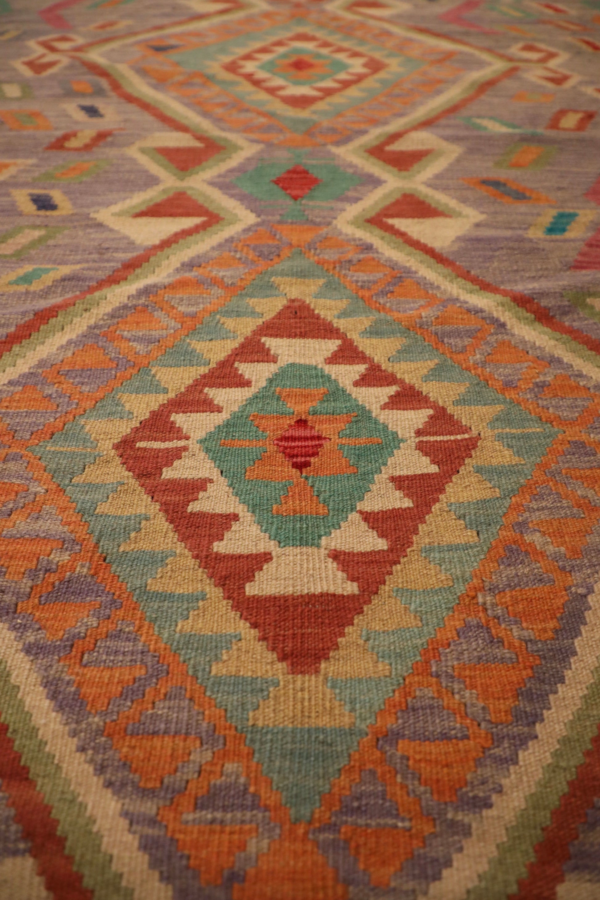 The Afghan Hand Woven Khyber Kilim - 127 X 174. Crafted using traditional vegetable dyed wool, and featuring traditional geometric designs. Colours, lavenders, beiges, creams, oranges. Size 127 X 174. Close.