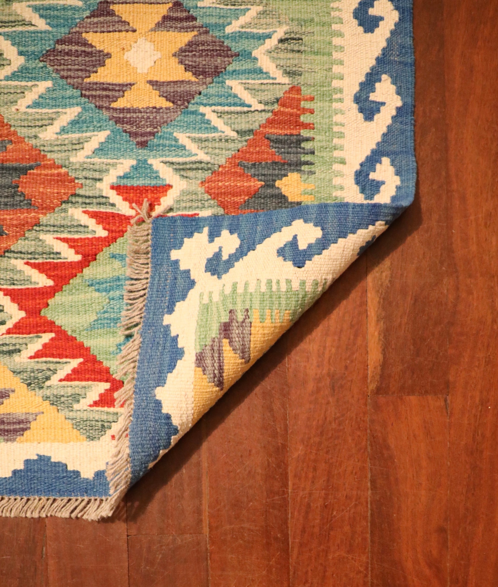The Afghan Hand Woven Khyber Kilim - 56 X 90. Crafted using traditional vegetable dyed wool, and featuring traditional geometric designs. Colours, ocean blues, light greens, light blues, reds, beiges, creams, oranges and yellows. Size 56 X 90. Fold.