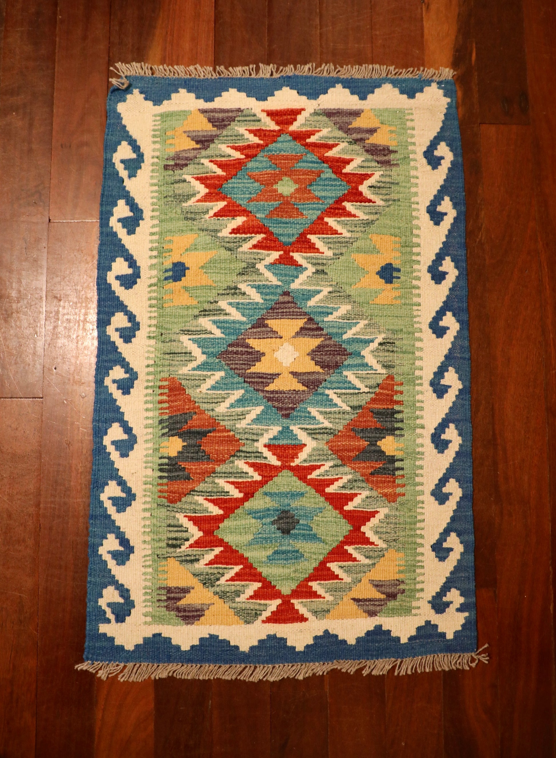 The Afghan Hand Woven Khyber Kilim - 56 X 90. Crafted using traditional vegetable dyed wool, and featuring traditional geometric designs. Colours, ocean blues, light greens, light blues, reds, beiges, creams, oranges and yellows. Size 56 X 90. Top.