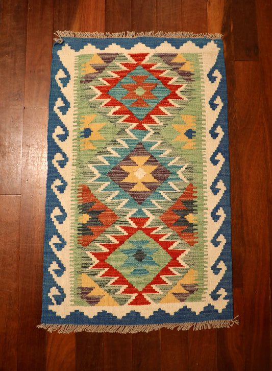The Afghan Hand Woven Khyber Kilim - 56 X 90. Crafted using traditional vegetable dyed wool, and featuring traditional geometric designs. Colours, ocean blues, light greens, light blues, reds, beiges, creams, oranges and yellows. Size 56 X 90. Top.