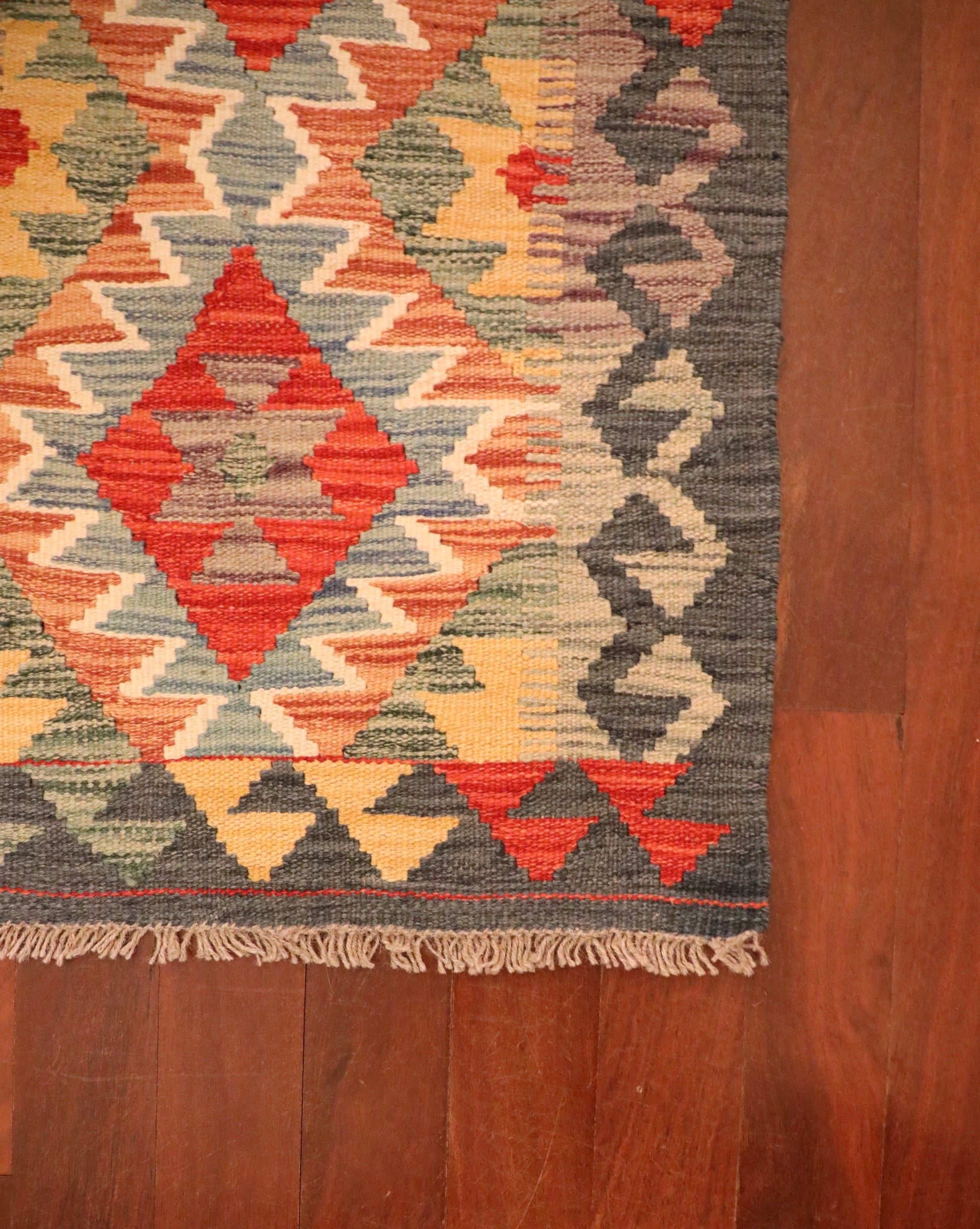 The Afghan Hand Woven Khyber Kilim - 57 X 91. Crafted using traditional vegetable dyed wool, and featuring traditional geometric designs. Colours, dark greys, beiges, blues, creams, light greens, light blues and yellows. Size 57 X 91. Corner.