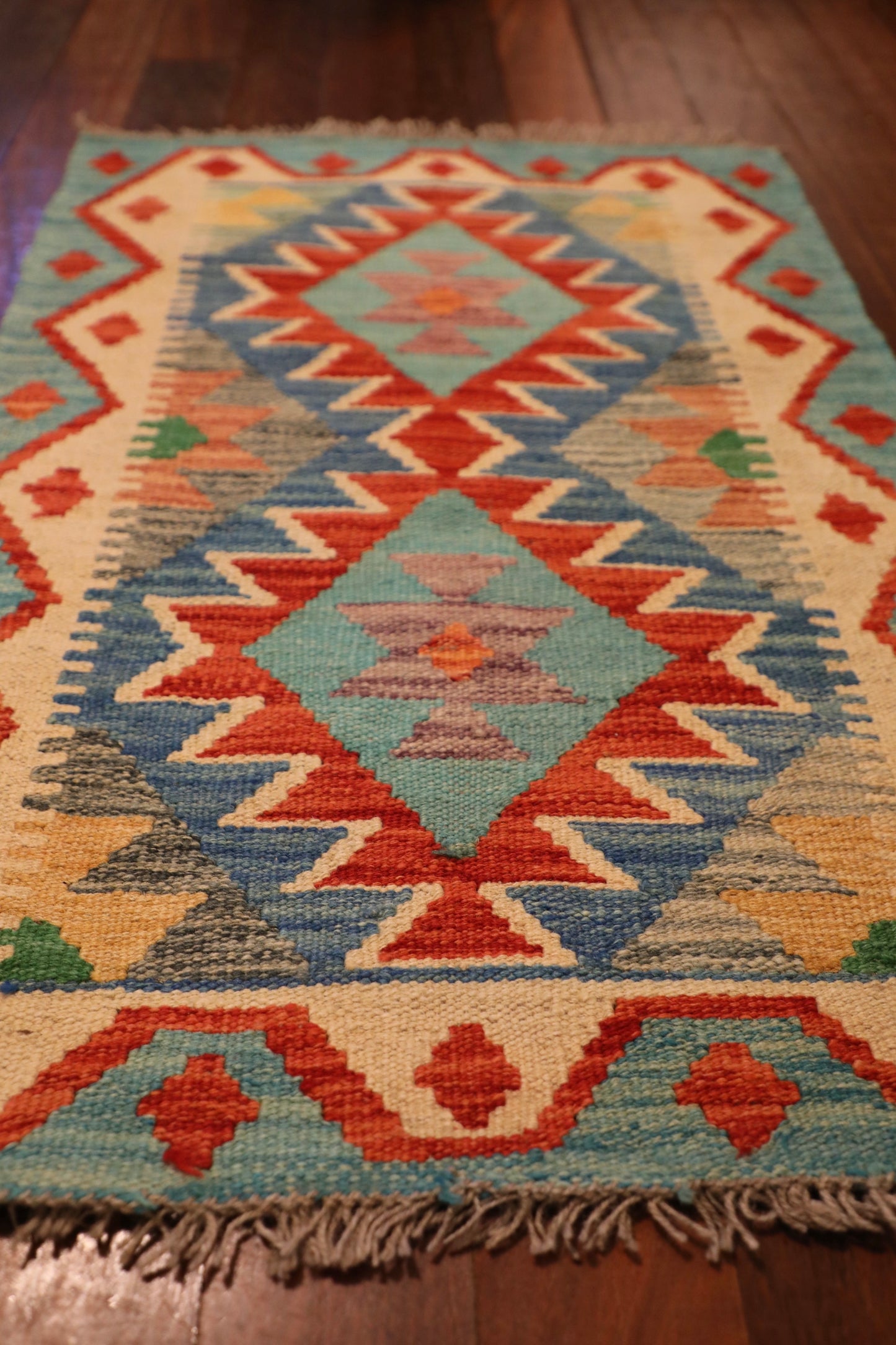  The Afghan Hand Woven Khyber Kilim - 58 X 88. Crafted using traditional vegetable dyed wool, and featuring traditional geometric designs. Colours, Dark oranges, creams, light greens, light blues yellows. Size 58 X 88. Angle.