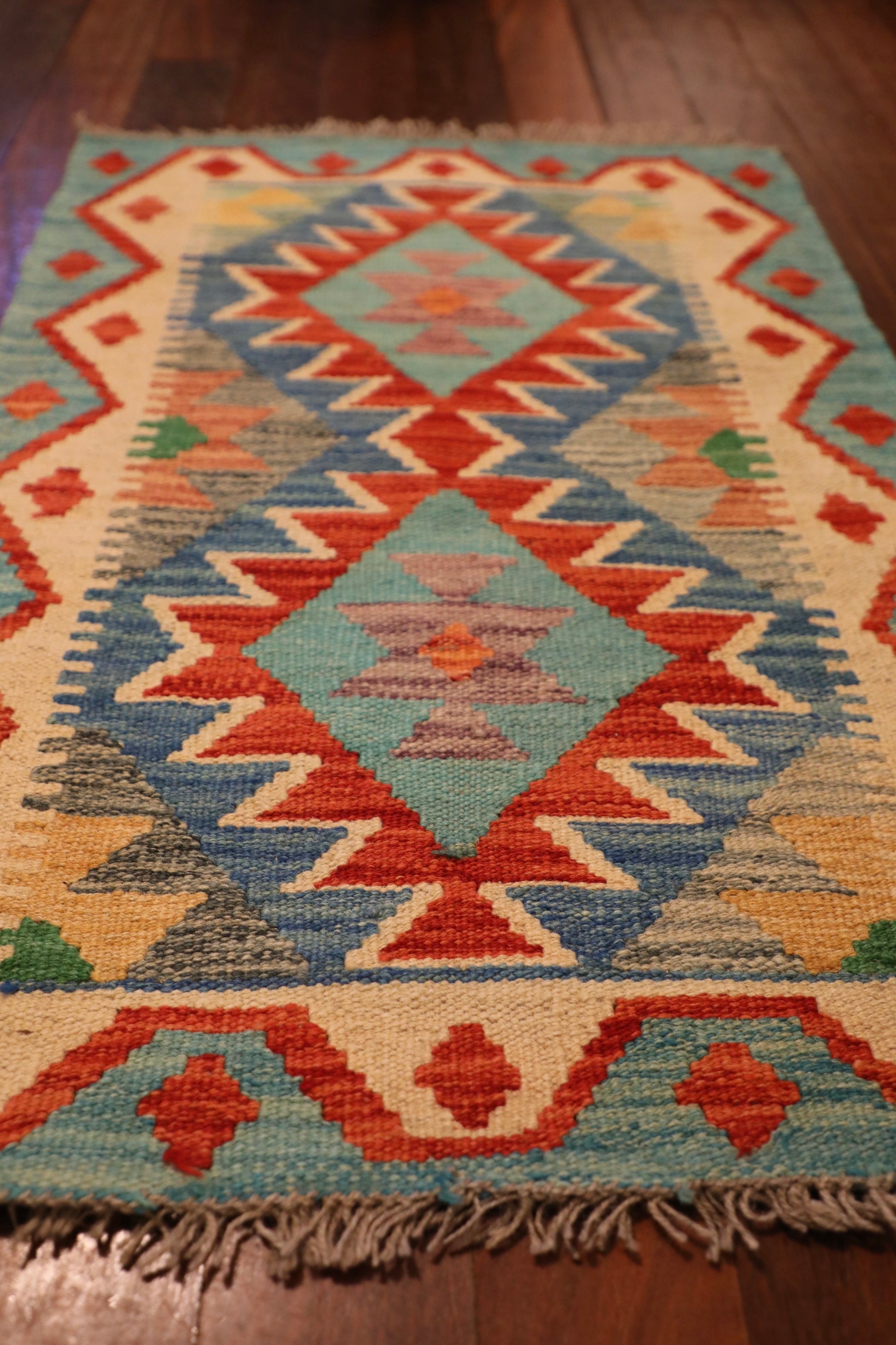  The Afghan Hand Woven Khyber Kilim - 58 X 88. Crafted using traditional vegetable dyed wool, and featuring traditional geometric designs. Colours, Dark oranges, creams, light greens, light blues yellows. Size 58 X 88. Angle.