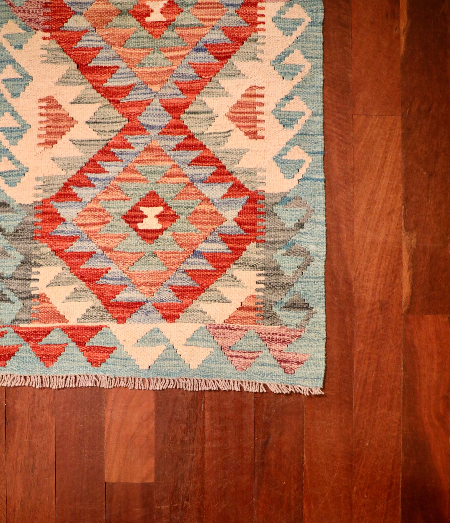 The Afghan Hand Woven Khyber Kilim - 59 X 88. Crafted using traditional vegetable dyed wool, and featuring traditional geometric designs. Colours, oranges, creams, light greens, light blues. Size 59 X 88. Corner.