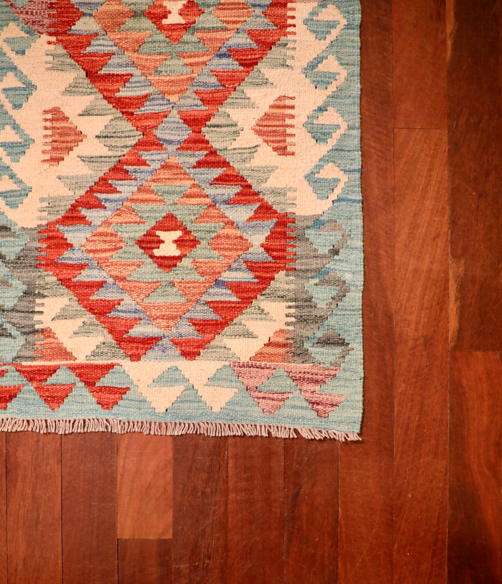 The Afghan Hand Woven Khyber Kilim - 59 X 88. Crafted using traditional vegetable dyed wool, and featuring traditional geometric designs. Colours, oranges, creams, light greens, light blues. Size 59 X 88. Corner.