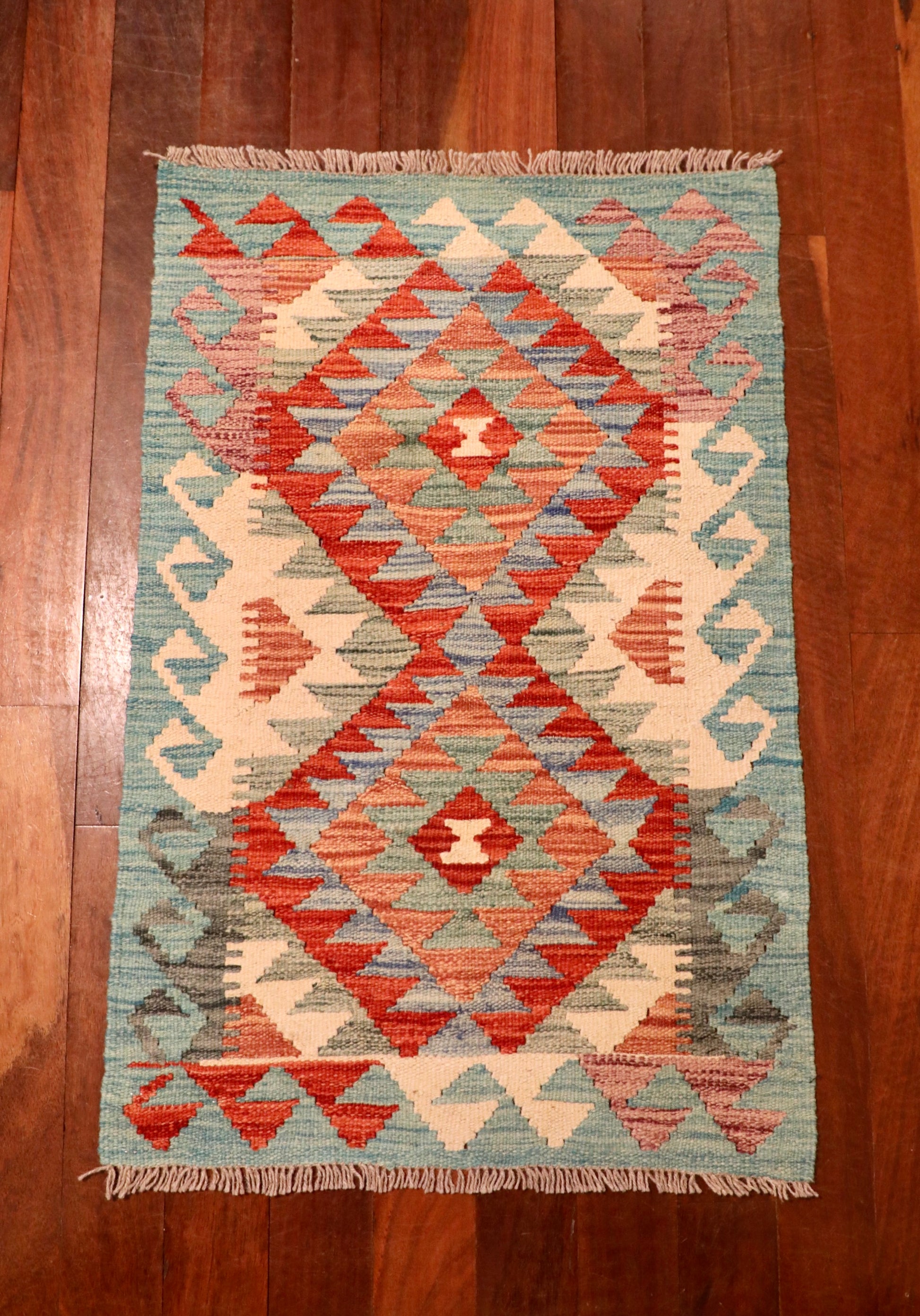 The Afghan Hand Woven Khyber Kilim - 59 X 88. Crafted using traditional vegetable dyed wool, and featuring traditional geometric designs. Colours, oranges, creams, light greens, light blues. Size 59 X 88. Top.