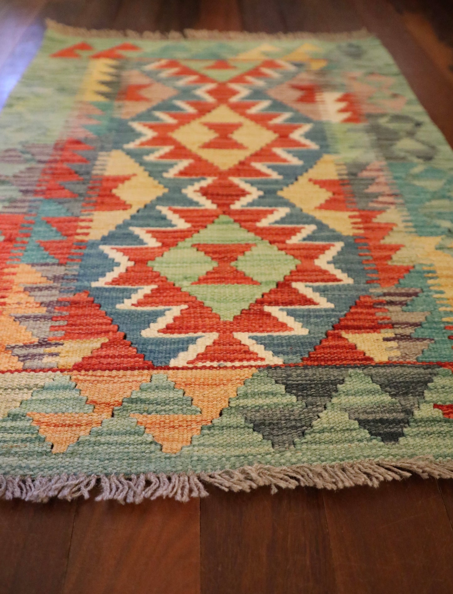 The Afghan Hand Woven Khyber Kilim - 60 X 85. Crafted using traditional vegetable dyed wool, and featuring traditional geometric designs. Colours, Dark oranges, creams, light greens, light blues yellows. Size 60 X 85. Angle.