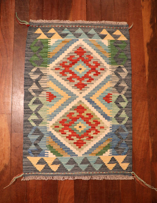 The Afghan Hand Woven Khyber Kilim - 60 X 88. Crafted using traditional vegetable dyed wool, and featuring traditional geometric designs. Colours, greys, creams, light blues, reds and orange. Size 60 wide X 88 length. Top.