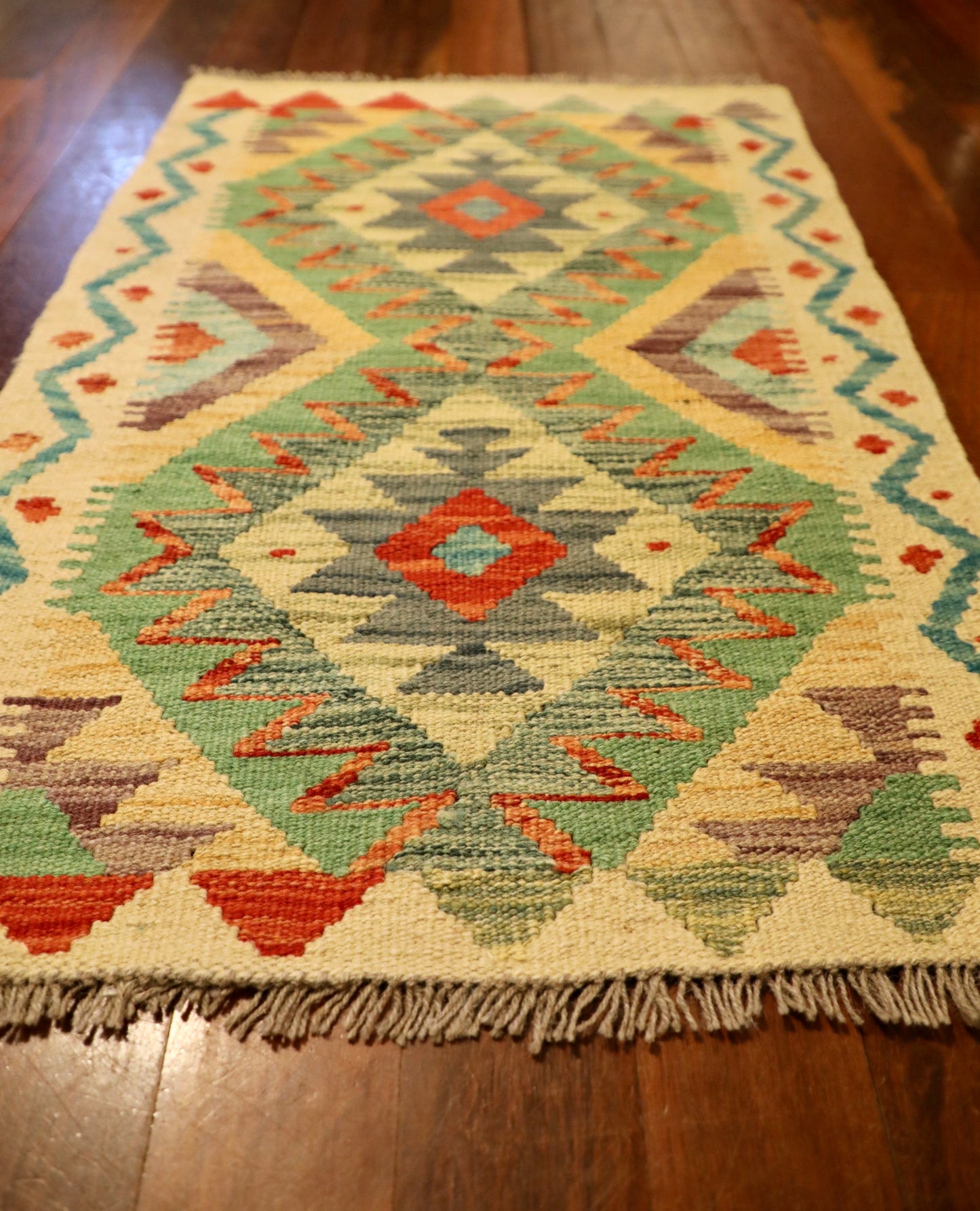 The Afghan Hand Woven Khyber Kilim 60 X 90. Crafted using traditional vegetable dyed wool, and featuring traditional geometric designs. Colours, beige, greens, light blues, yellows and reds. Size 60 X 90. Angle.