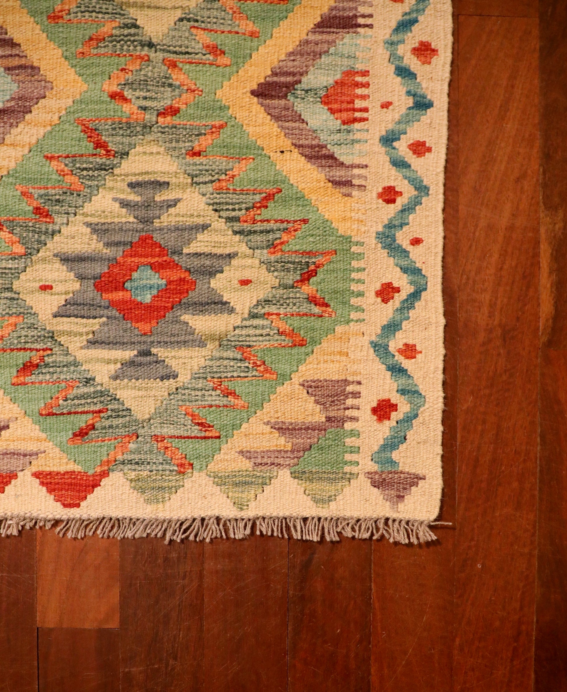 The Afghan Hand Woven Khyber Kilim 60 X 90. Crafted using traditional vegetable dyed wool, and featuring traditional geometric designs. Colours, beige, greens, light blues, yellows and reds. Size 60 X 90. Corner.