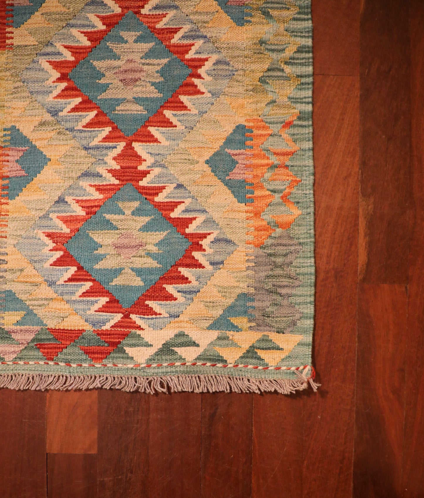The Afghan Hand Woven Khyber Kilim - 60 X 91. Crafted using traditional vegetable dyed wool, and featuring traditional geometric designs. Colours, Greens, beiges, yellows, creams, oranges, light blues. Size 60 X 91. Corner.