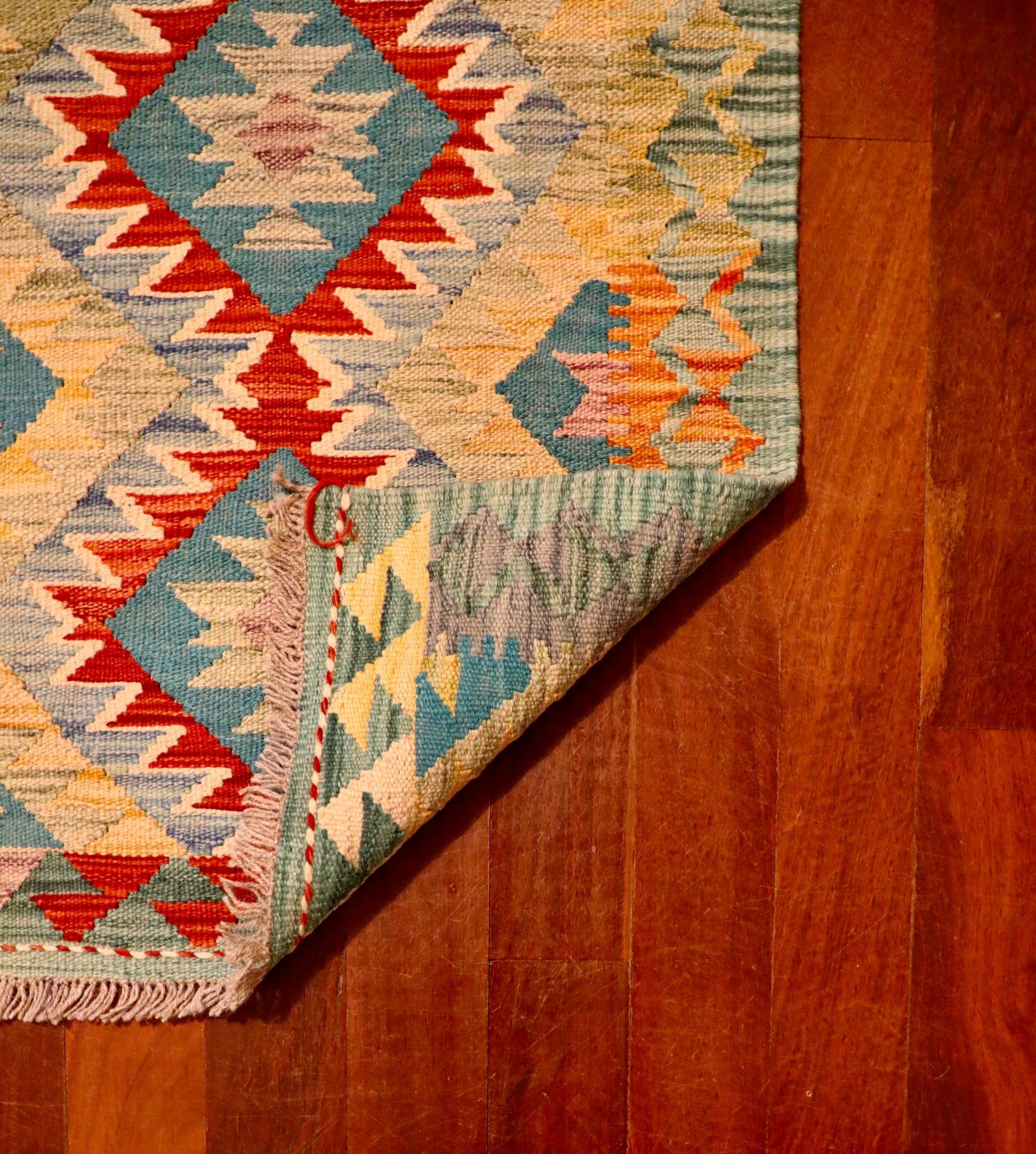 The Afghan Hand Woven Khyber Kilim - 60 X 91. Crafted using traditional vegetable dyed wool, and featuring traditional geometric designs. Colours, Greens, beiges, yellows, creams, oranges, light blues. Size 60 X 91. Fold.