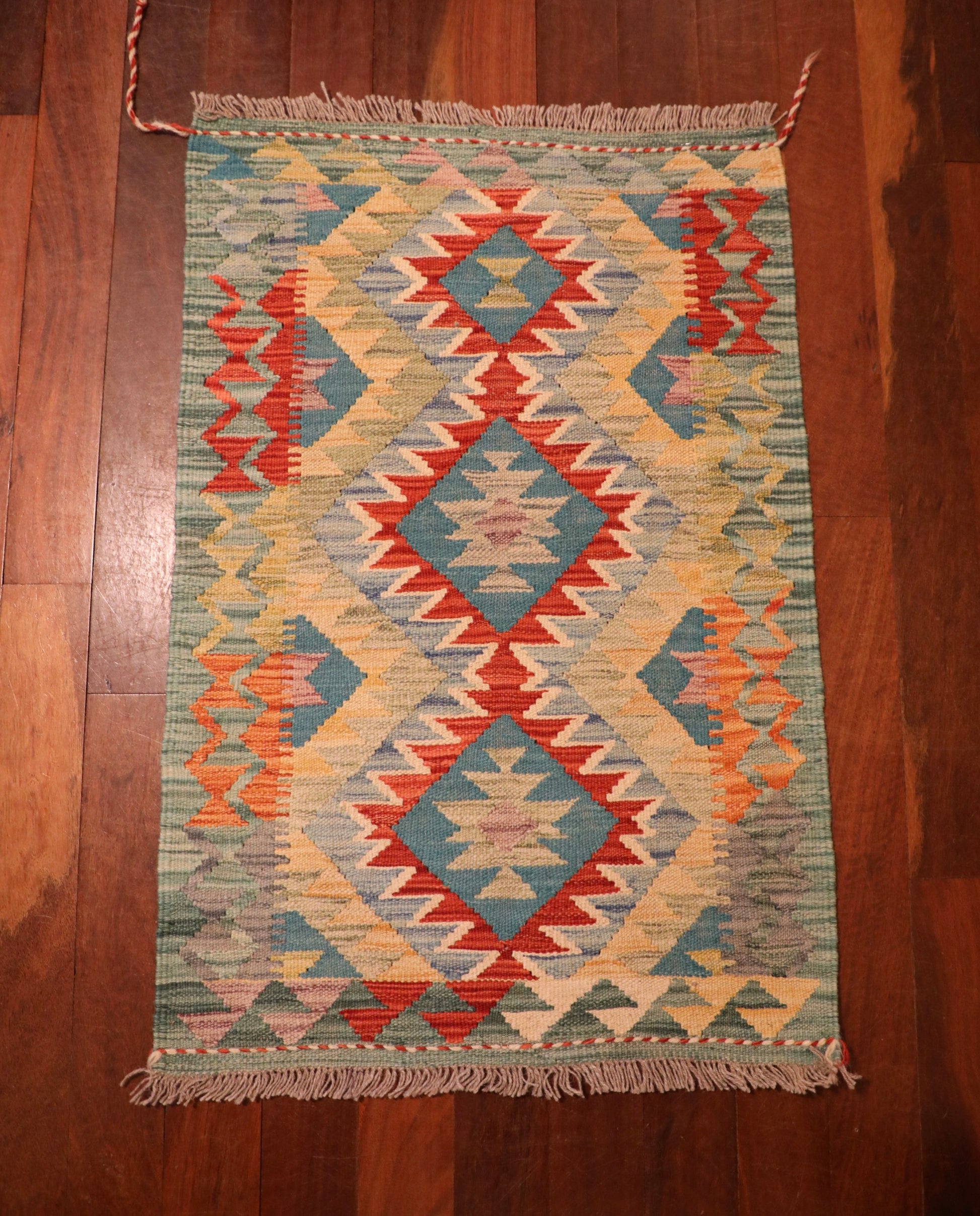 The Afghan Hand Woven Khyber Kilim - 60 X 91. Crafted using traditional vegetable dyed wool, and featuring traditional geometric designs. Colours, Greens, beiges, yellows, creams, oranges, light blues. Size 60 X 91. Top.