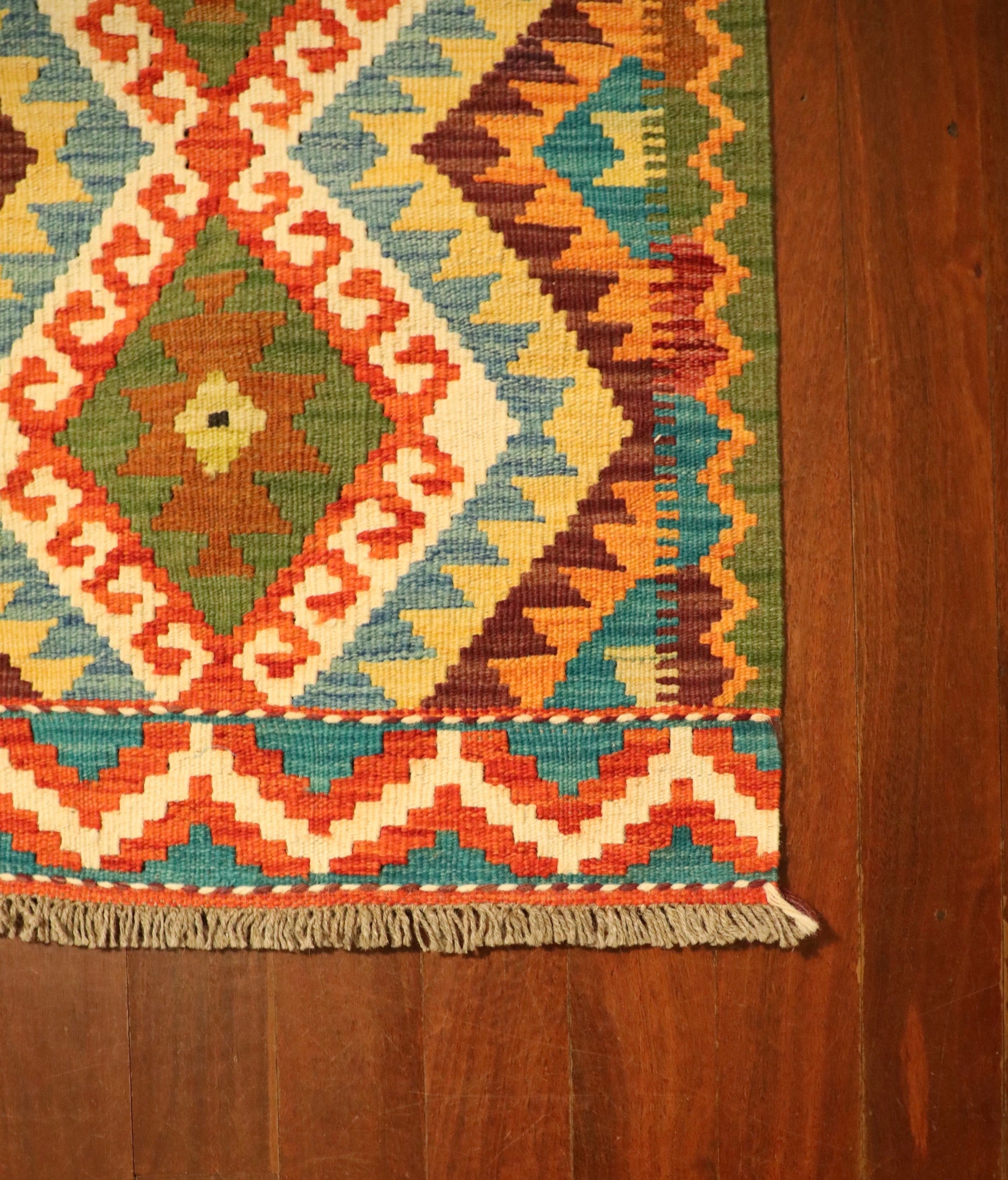 The Afghan Hand Woven Khyber Kilim - 62 X 87. Crafted using traditional vegetable dyed wool, and featuring traditional geometric designs. Colours, reds, beiges, creams, oranges, light greens, light blues and yellows. Size 62 X 87. Corner.