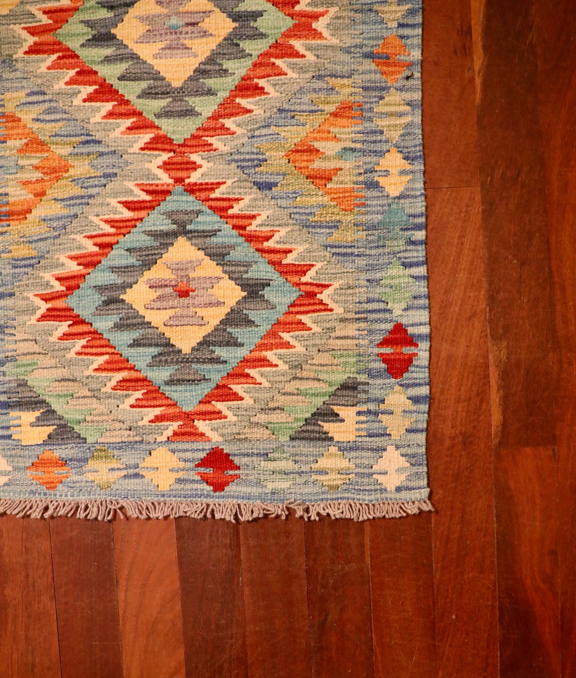 The Afghan Hand Woven Khyber Kilim - 64 X 86. Crafted using traditional vegetable dyed wool, and featuring traditional geometric designs. Colours, creams, light blues, reds and orange. Size 64 wide X 86 length. Corner.