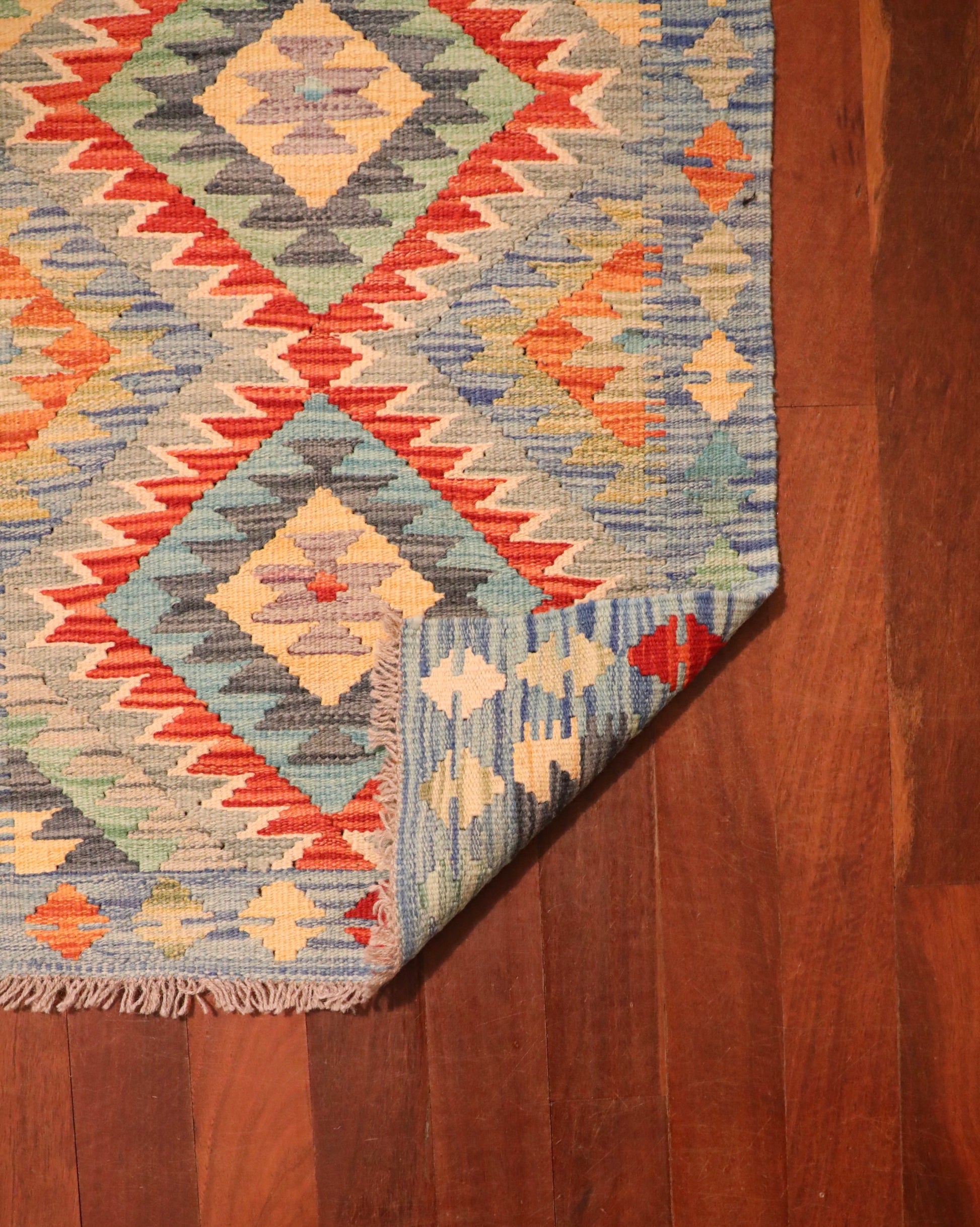 The Afghan Hand Woven Khyber Kilim - 64 X 86. Crafted using traditional vegetable dyed wool, and featuring traditional geometric designs. Colours, creams, light blues, reds and orange. Size 64 wide X 86 length. Fold.