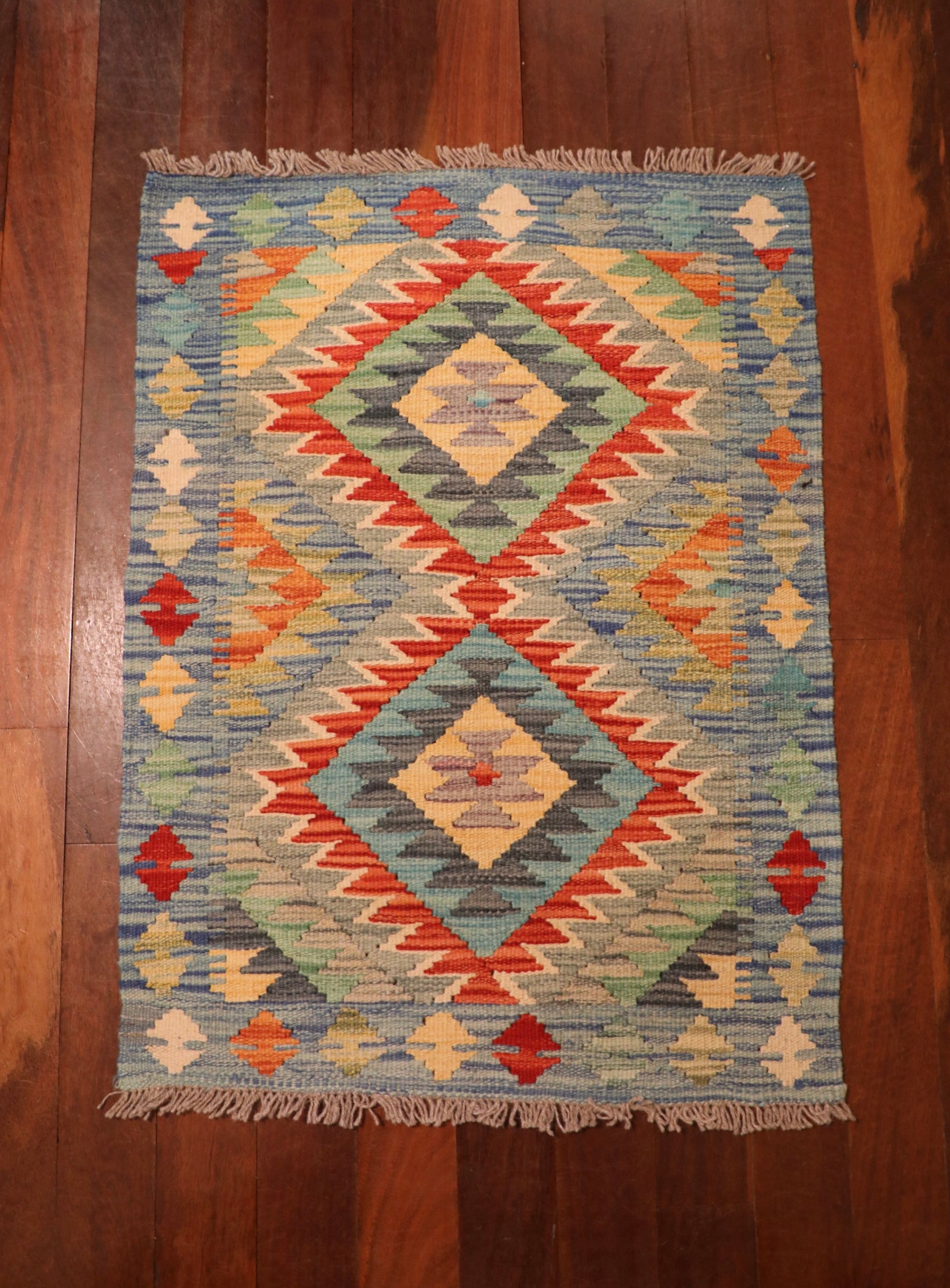 The Afghan Hand Woven Khyber Kilim - 64 X 86. Crafted using traditional vegetable dyed wool, and featuring traditional geometric designs. Colours, creams, light blues, reds and orange. Size 64 wide X 86 length. Top.