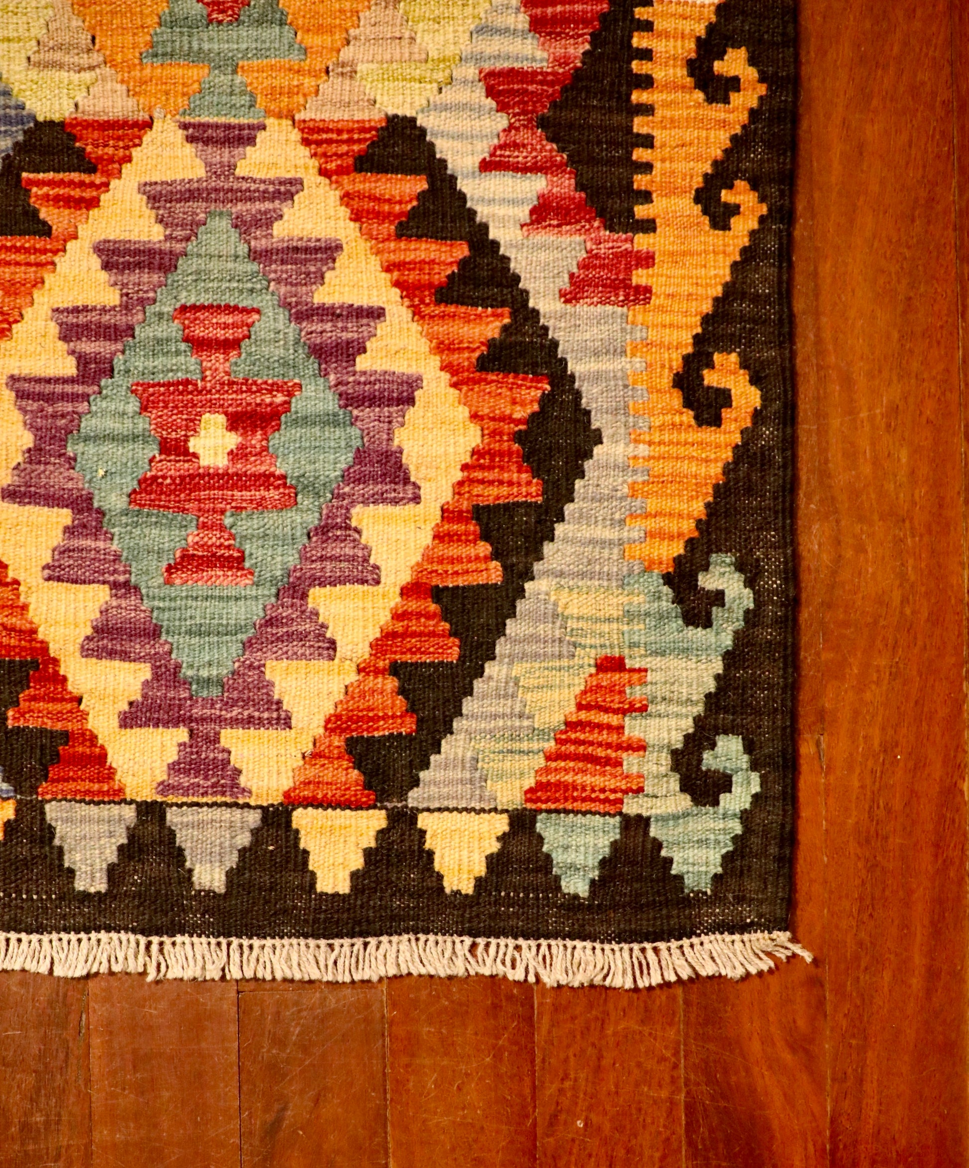 The Afghan Hand Woven Khyber Kilim - 65 X 87. Crafted using traditional vegetable dyed wool, and featuring traditional geometric designs. Colours, navy blue, reds, beiges, creams, oranges, light greens, light blues and yellows. Size 65 X 87. Corner.